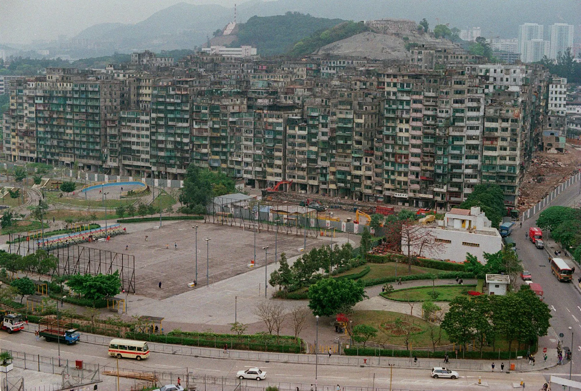 Foto histórica em preto e branco da Cidade Murada de Kowloon, mostrando uma massa de prédios empilhados.