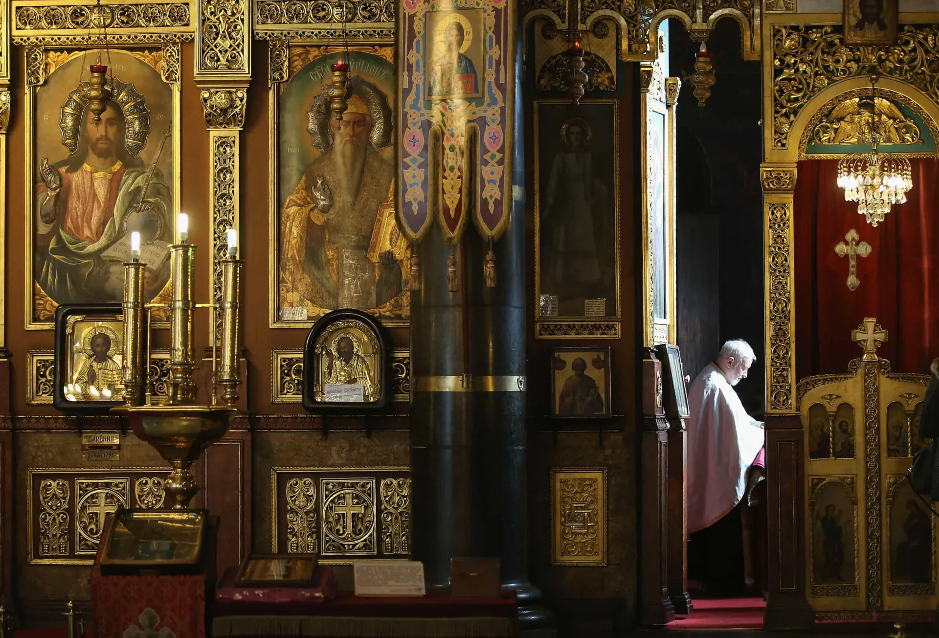 Interior de uma igreja ortodoxa com ícones dourados e decoração elaborada.