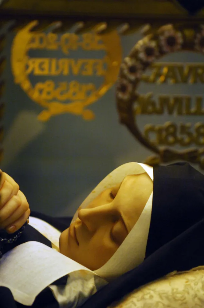 Corpo de Santa Bernadette de Lourdes coberto por uma fina camada de cera, em exposição em uma urna de vidro.