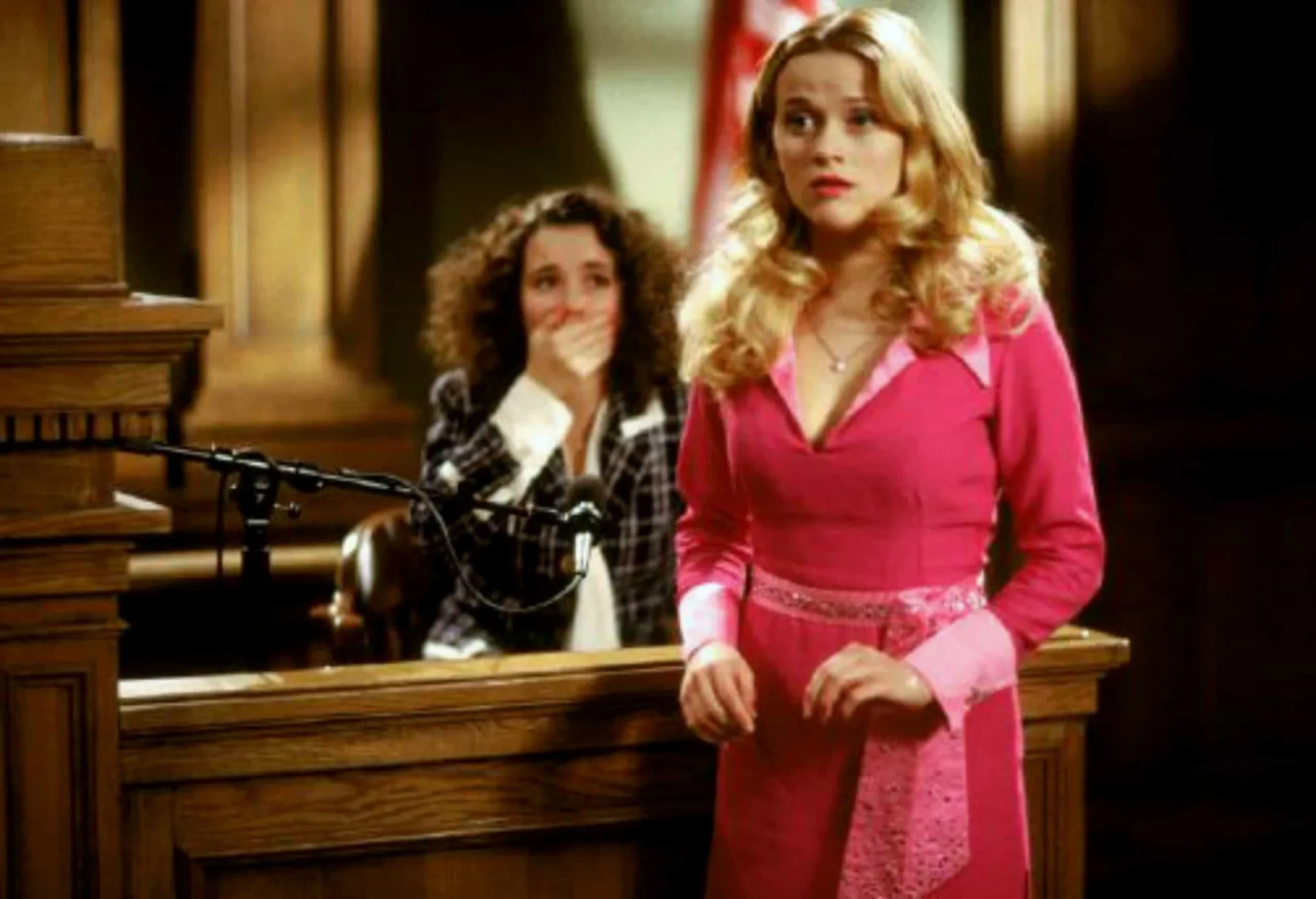 Reese Witherspoon como Elle Woods em 'Legalmente Loira', triunfando na faculdade de direito.