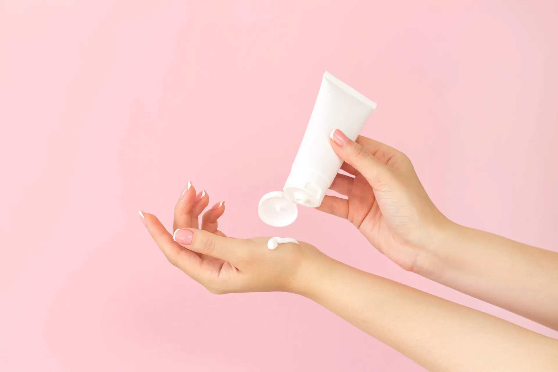Uma pessoa aplicando creme hidratante nas mãos e cutículas.