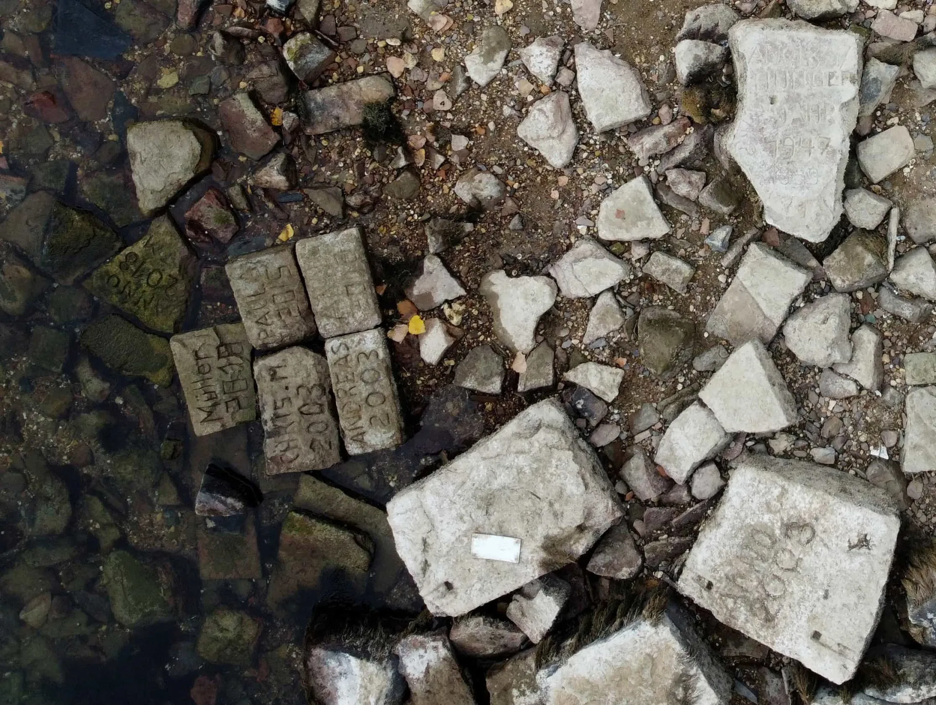 Uma 'pedra da fome' com inscrições e datas esculpidas, exposta na margem seca do Rio Reno.