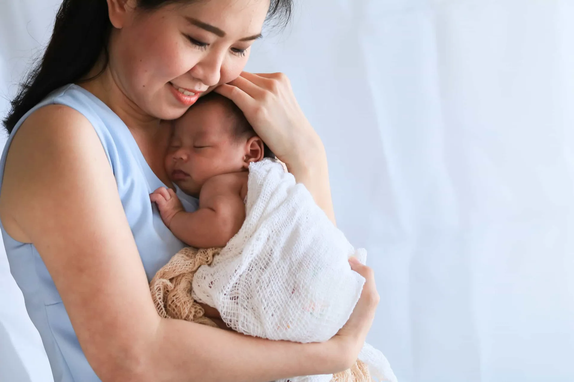 Uma mãe acariciando seu bebê, que sorri, ilustrando a importância do toque no desenvolvimento.