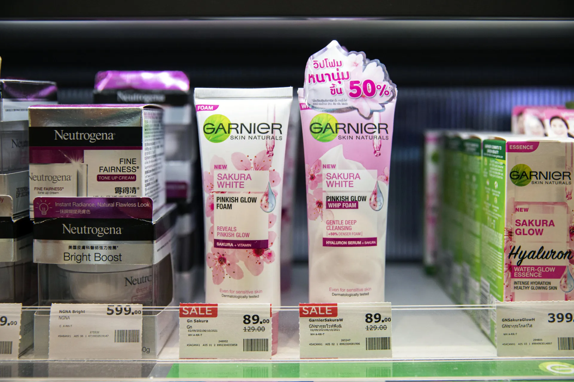 Mão fazendo um sinal de 'pare' em frente a prateleiras de cosméticos.