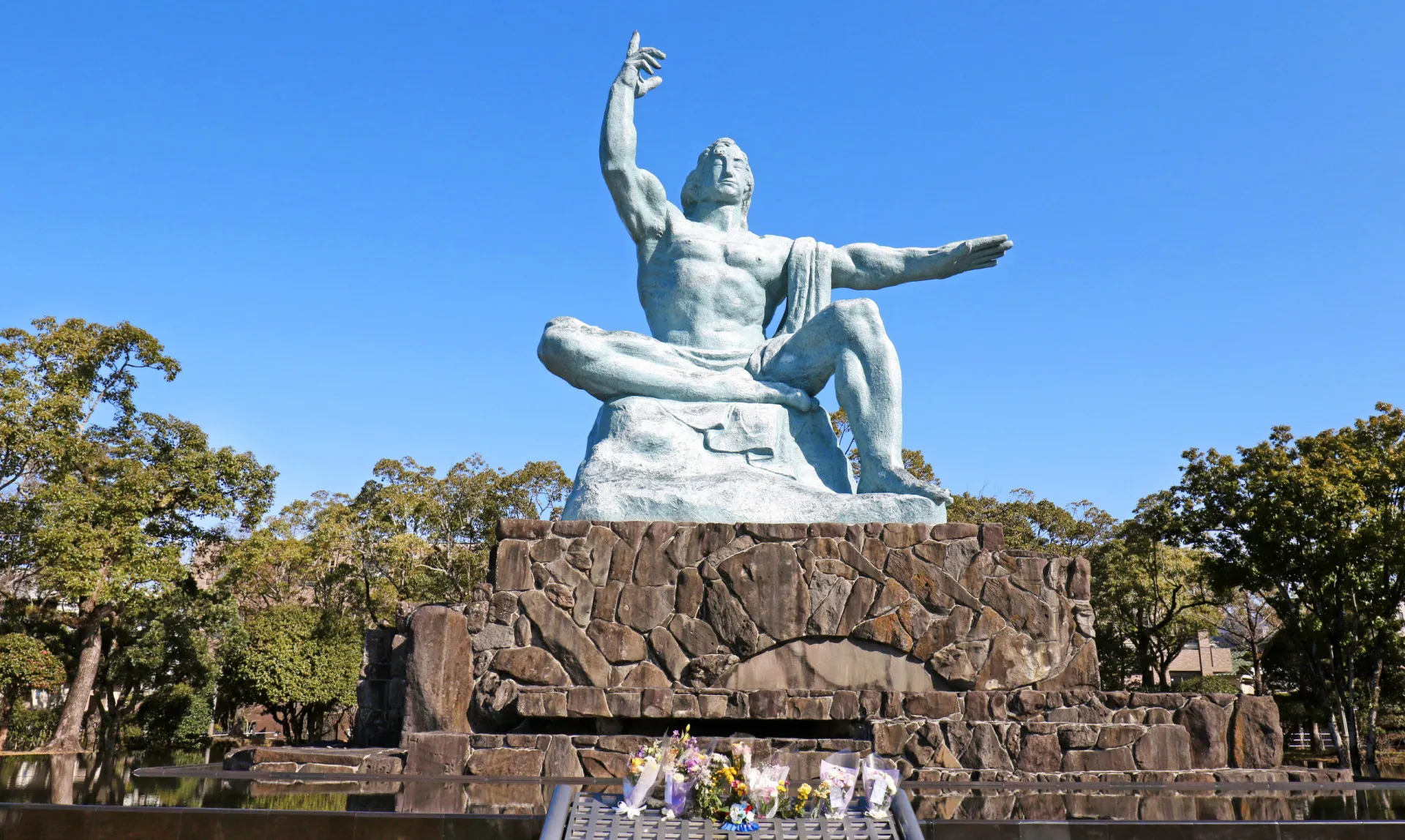 A imponente Estátua da Paz em Nagasaki, com uma mão apontando para o céu e a outra estendida horizontalmente.