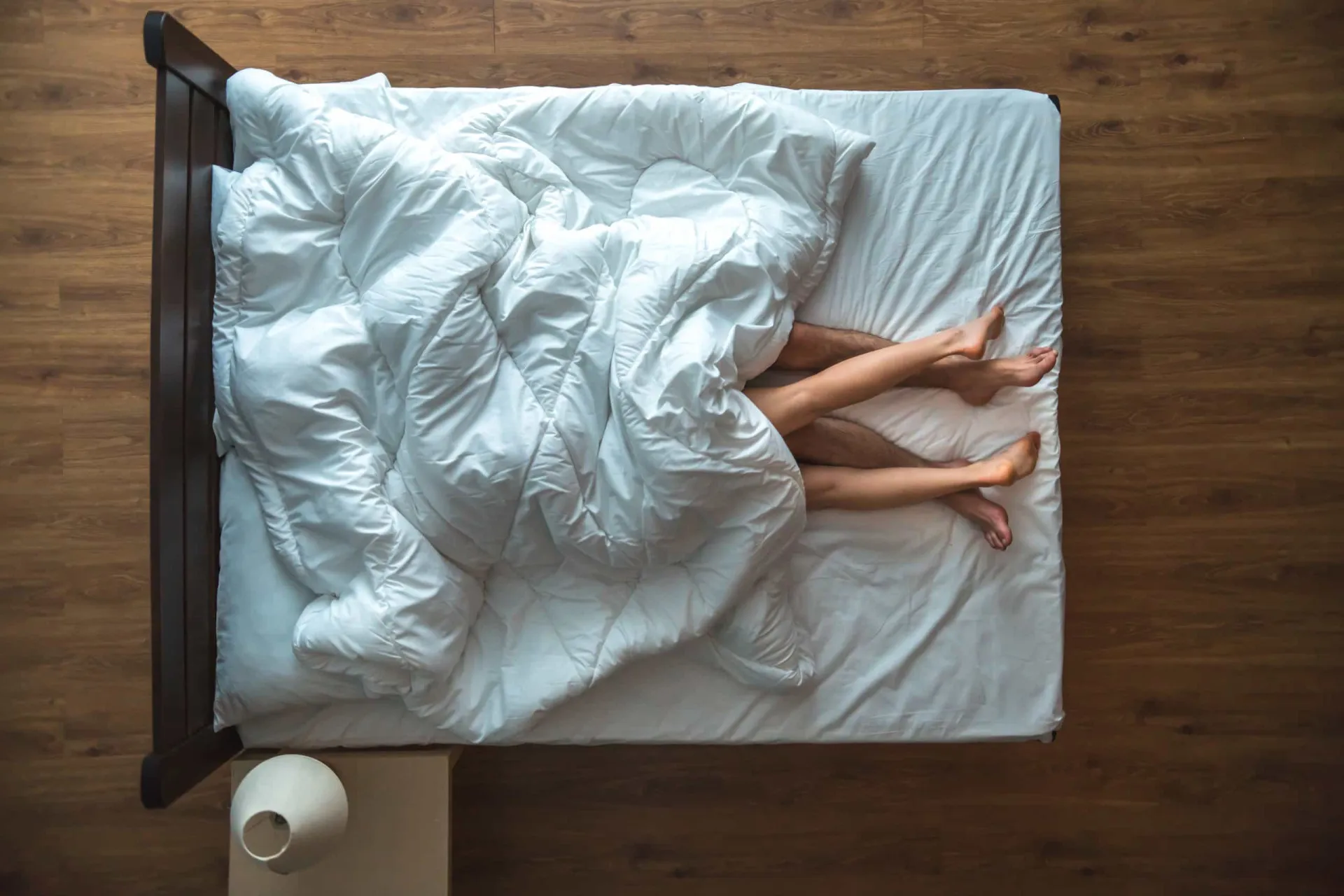 Um casal abraçado na cama, com uma expressão de preocupação e cansaço em seus rostos.