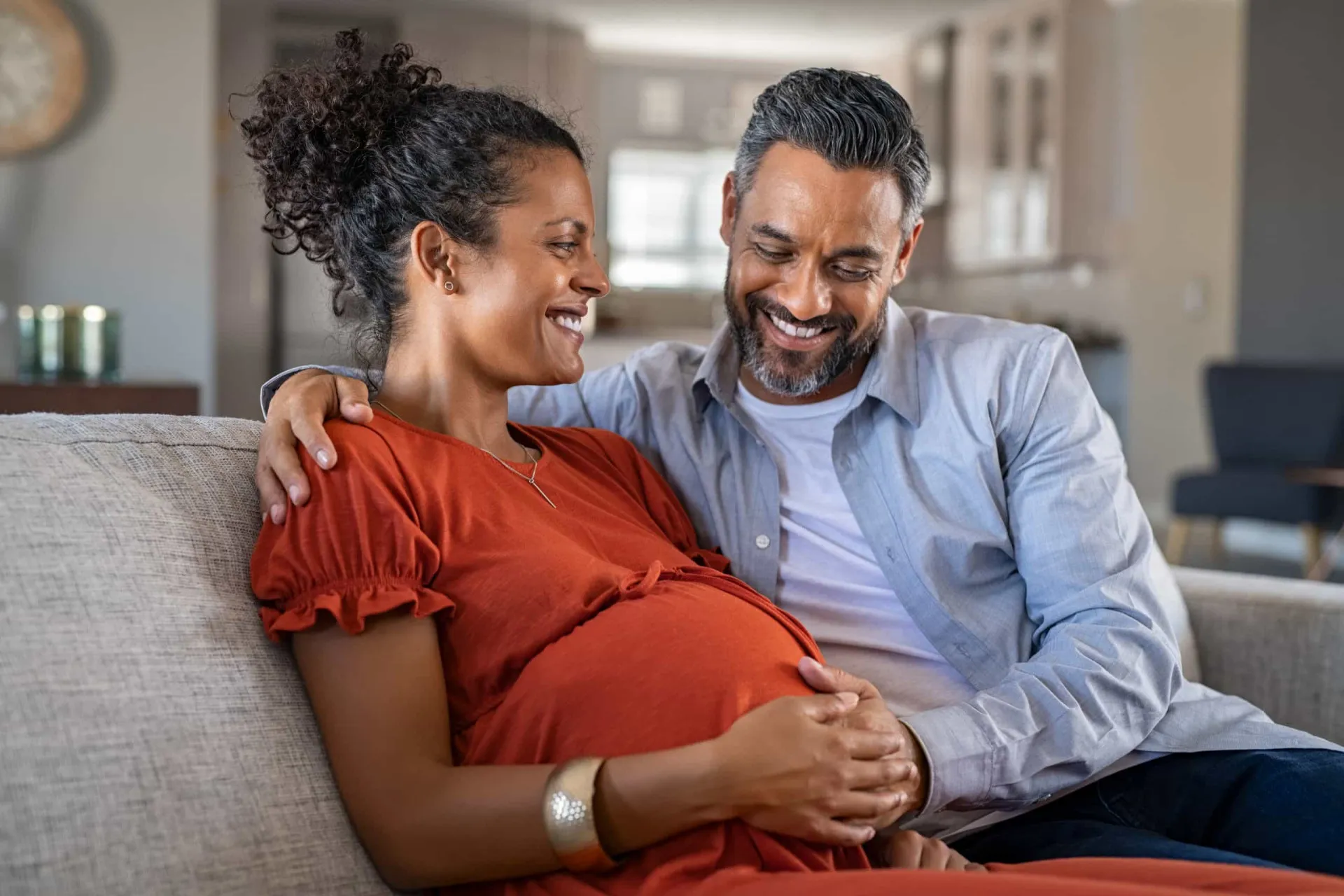 Uma mulher sorridente com mais de 35 anos, parecendo feliz e confiante em sua jornada de maternidade.