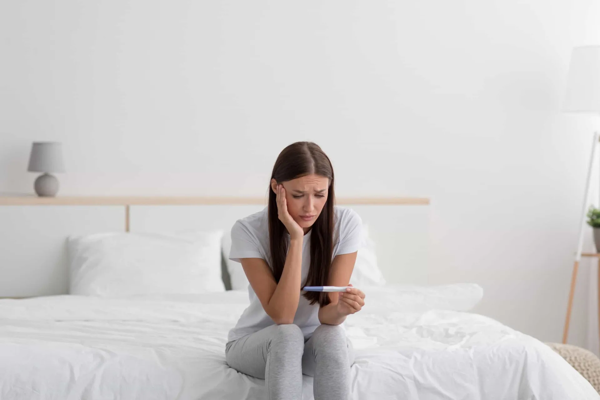 Um homem e uma mulher sentados de costas um para o outro, simbolizando a divisão e a culpa na infertilidade.
