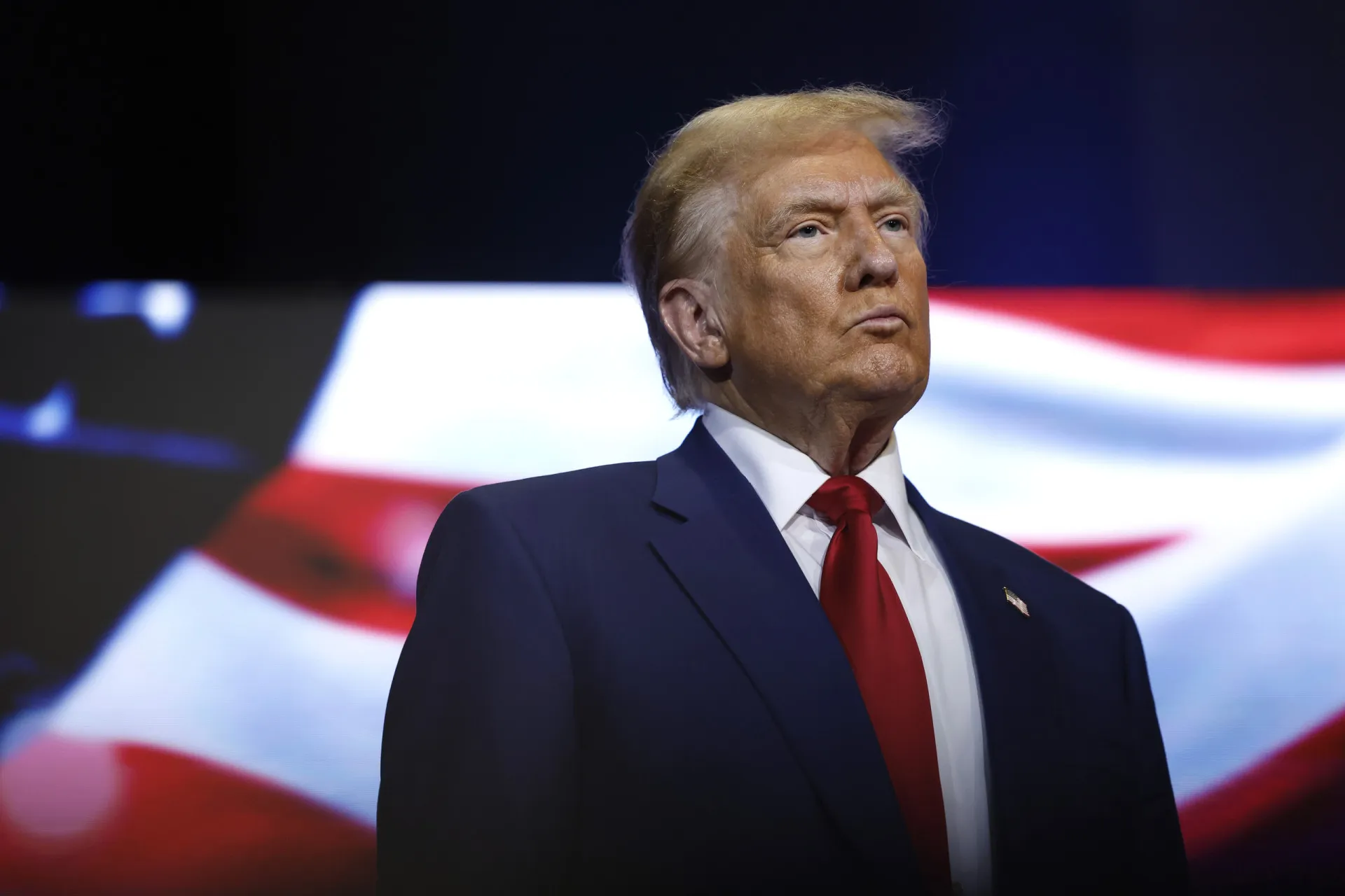 Donald Trump em um comício, falando energicamente para uma grande multidão.