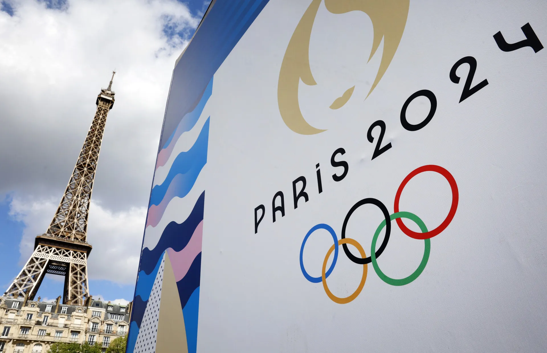 A pira olímpica acesa com a Torre Eiffel ao fundo durante os Jogos de Paris 2024.