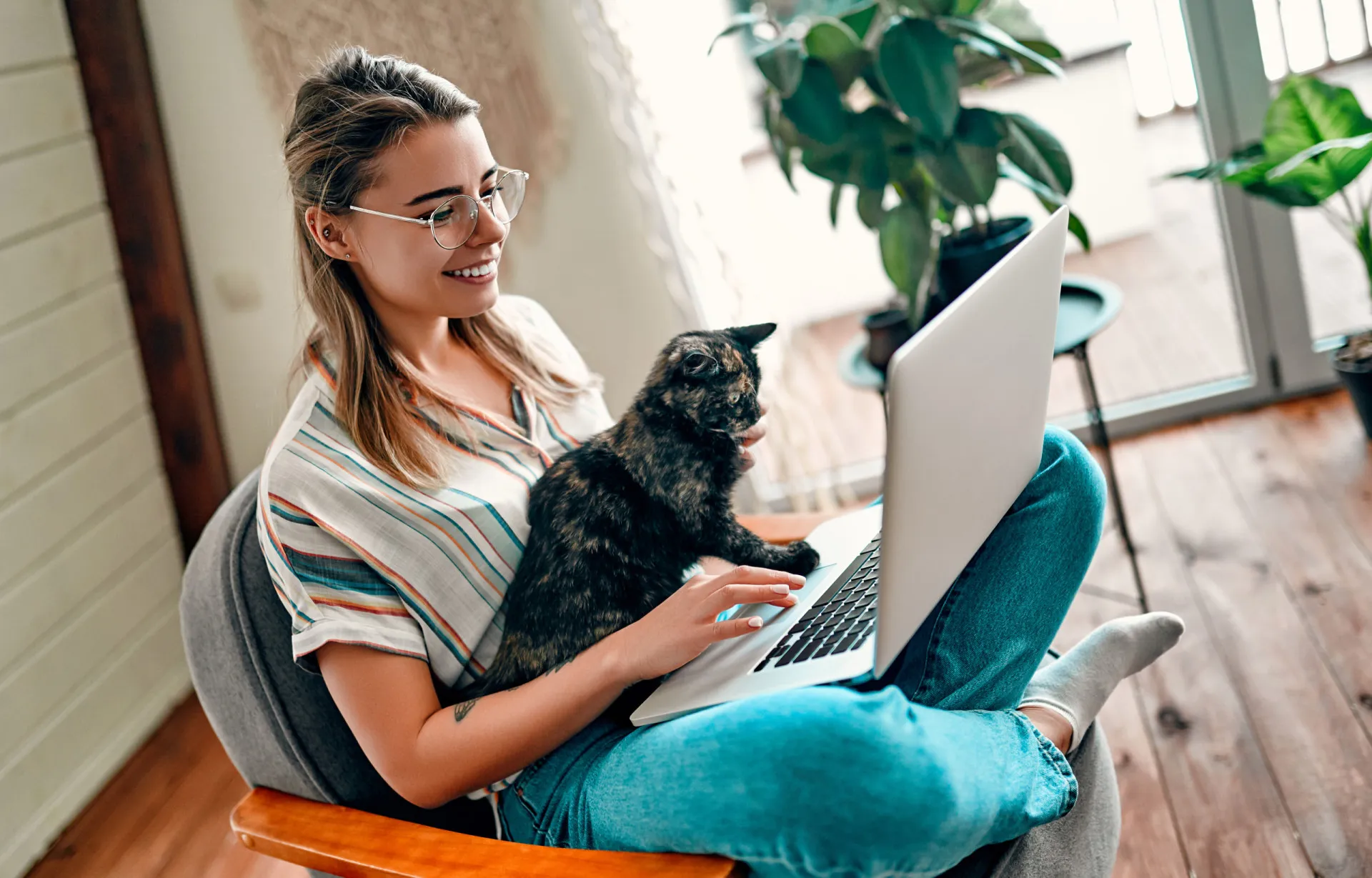 Pessoa trabalhando de forma autônoma em um café com um gato dormindo na cadeira ao lado.