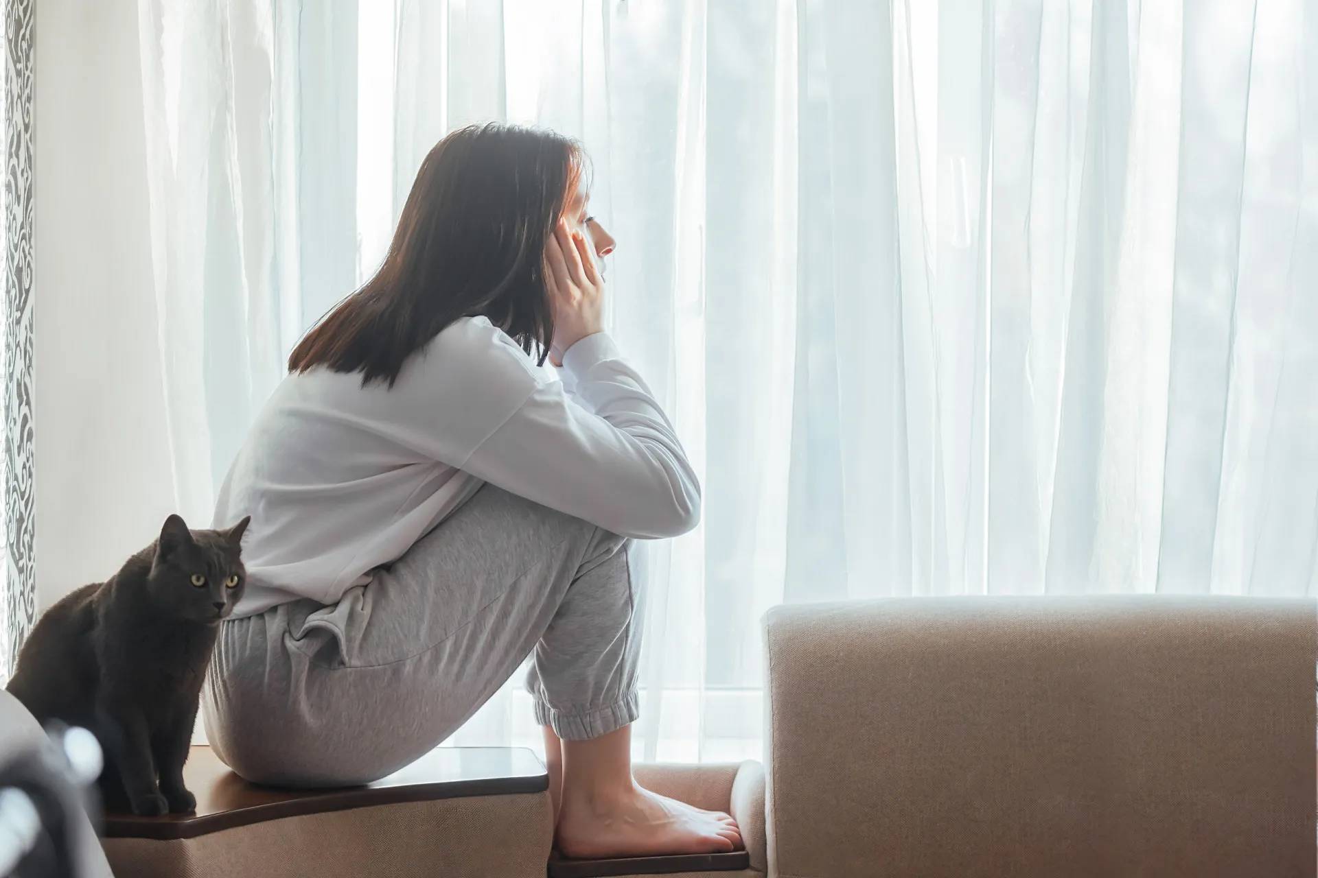 Mulher com expressão de preocupação e ansiedade, sentada em um ambiente interno.