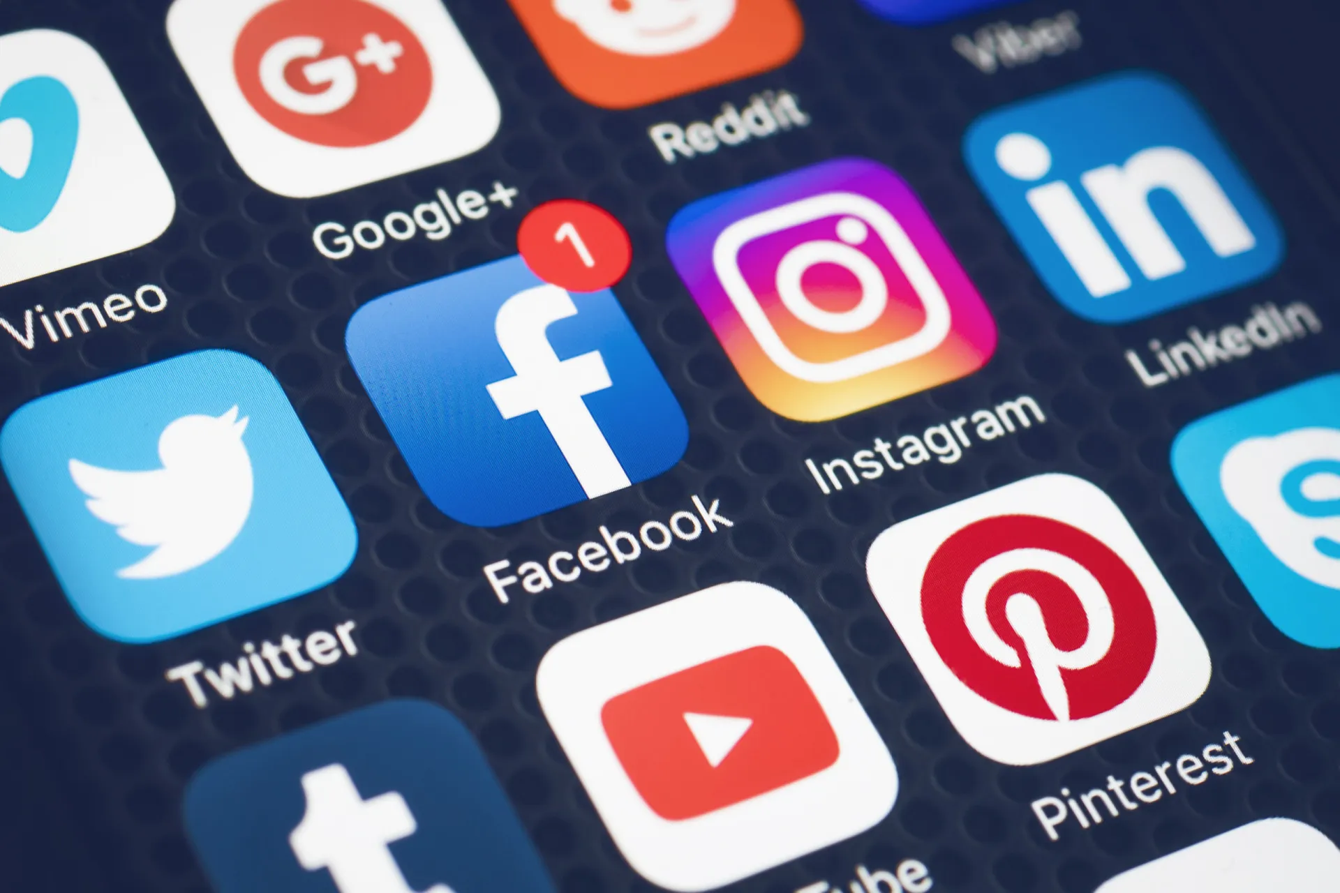 Uma mão segurando um smartphone com ícones de redes sociais flutuando ao redor.