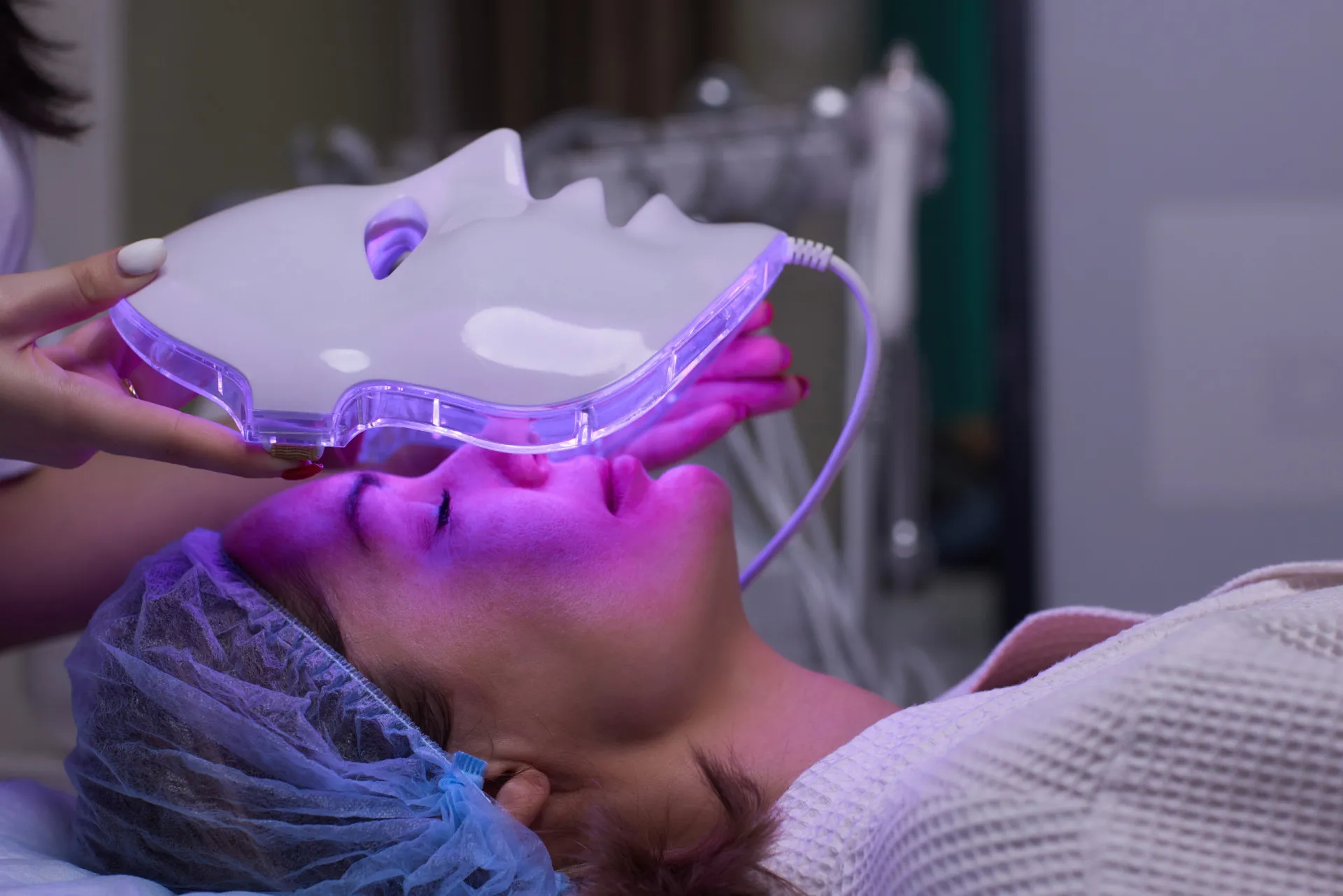 Máscara de Ledterapia facial com luz vermelha acesa no rosto de uma mulher.