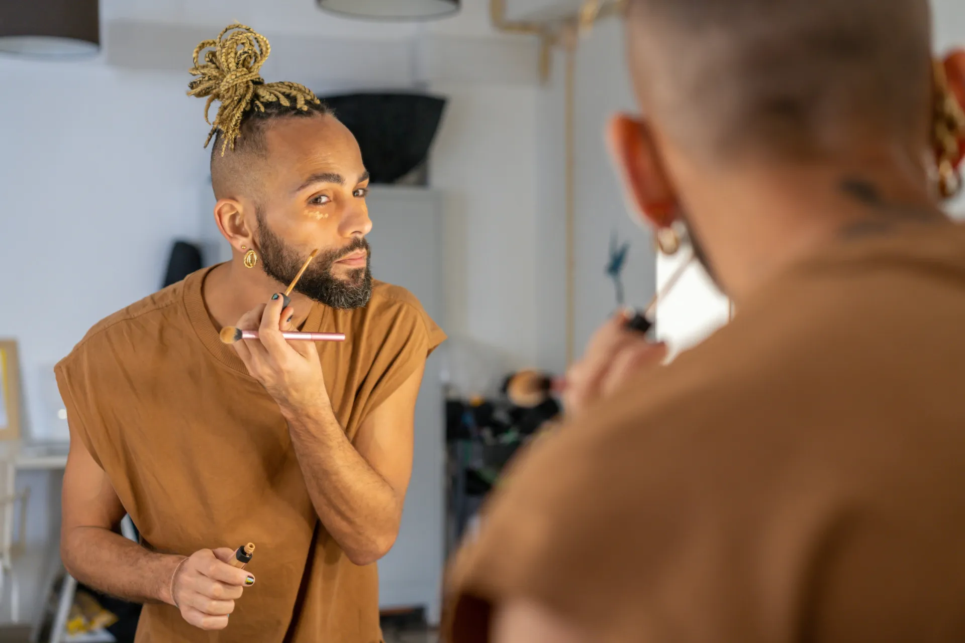Modelo com pele oliva vestindo um look em tons de verde musgo, dourado e marrom.