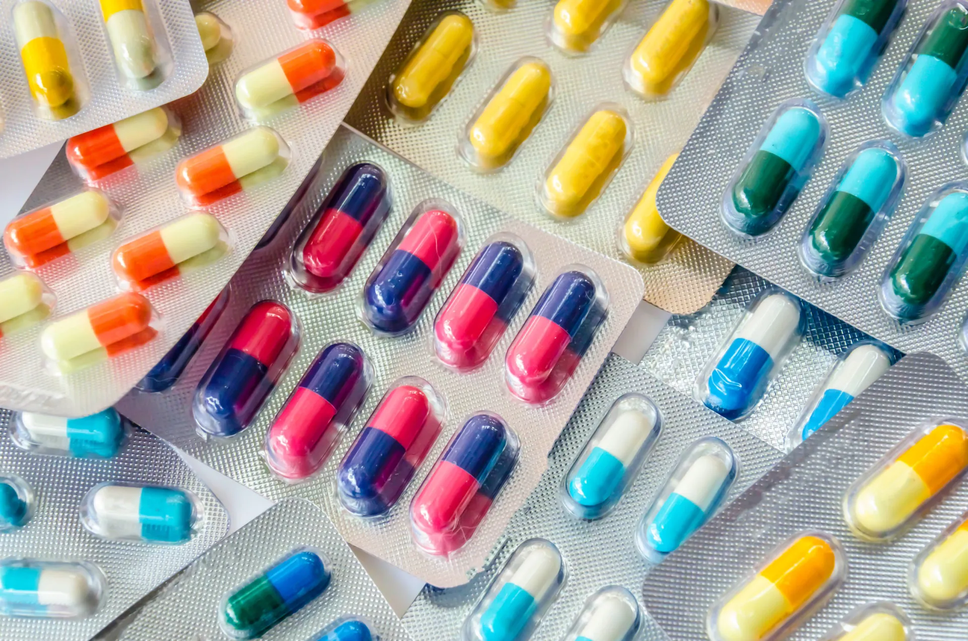 Uma variedade de pílulas e cápsulas de antibióticos coloridos sobre uma superfície limpa.