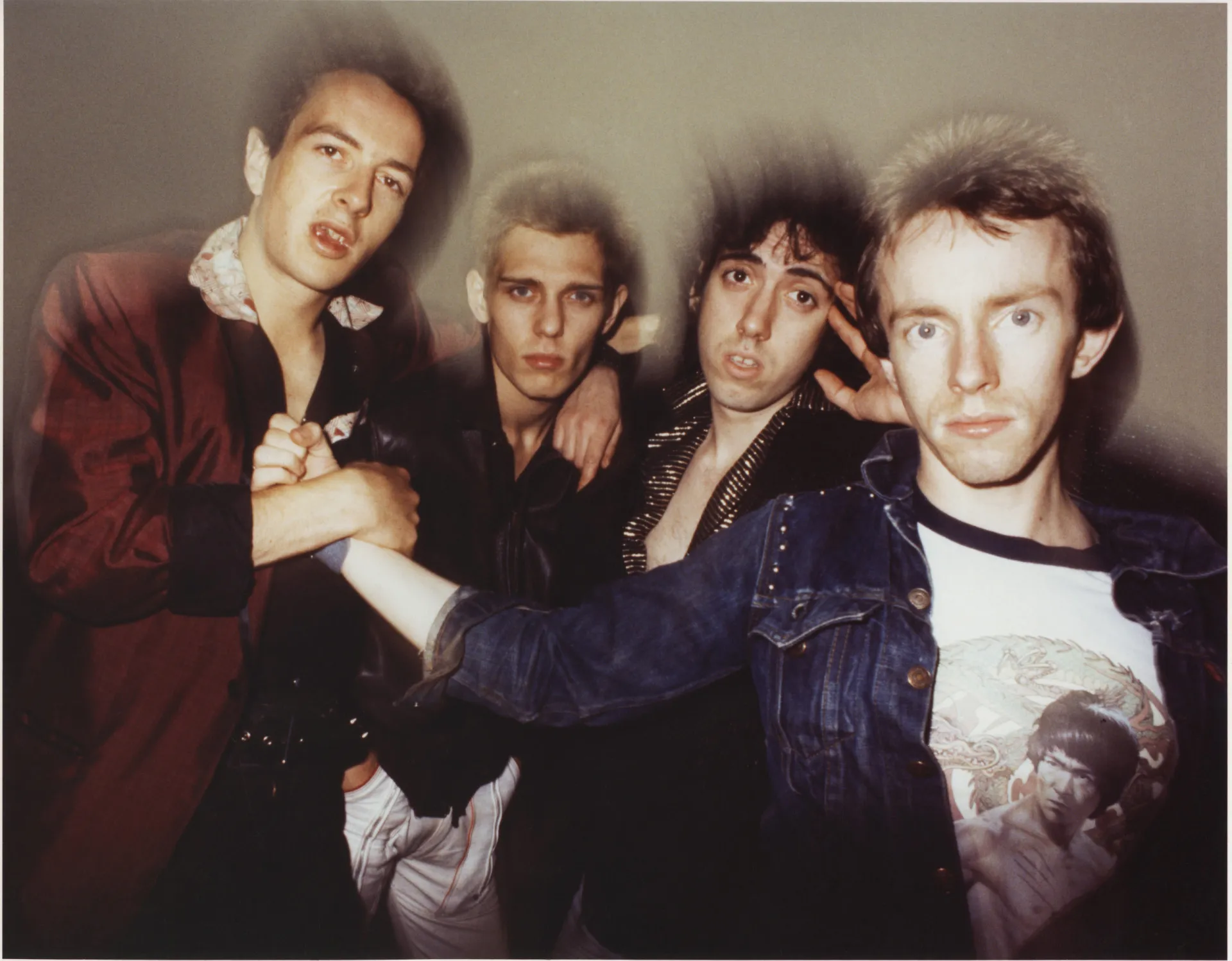 Joe Strummer, da banda The Clash, em uma pose enérgica e icônica no palco.