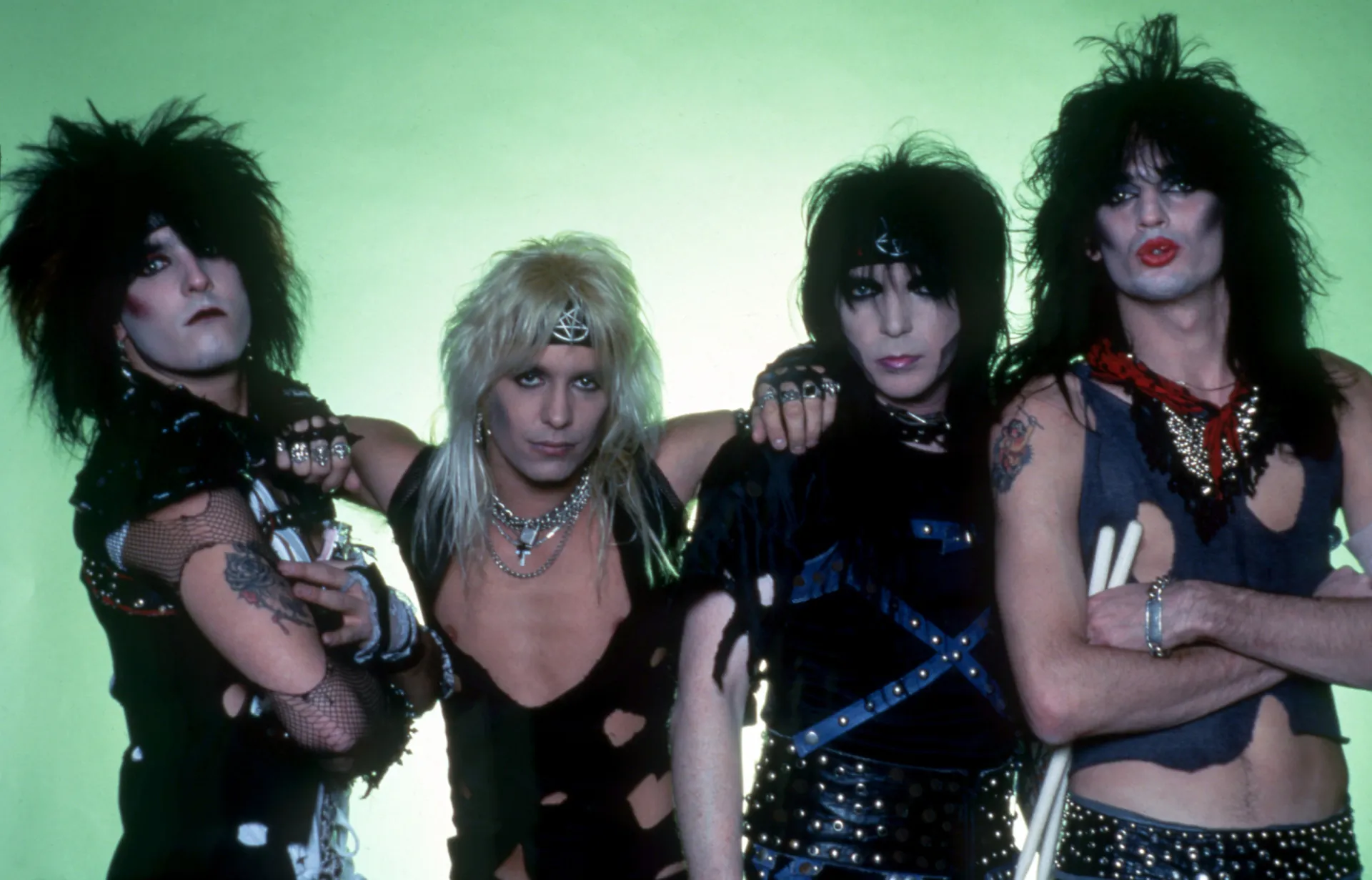 A banda Mötley Crüe com seus cabelos volumosos e roupas de couro características dos anos 80.