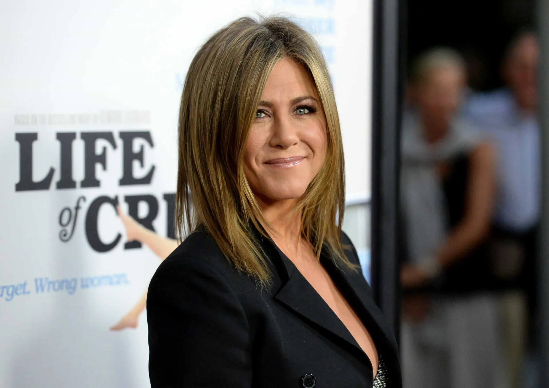 Jennifer Aniston posando de perfil, destacando sua pele saudável.