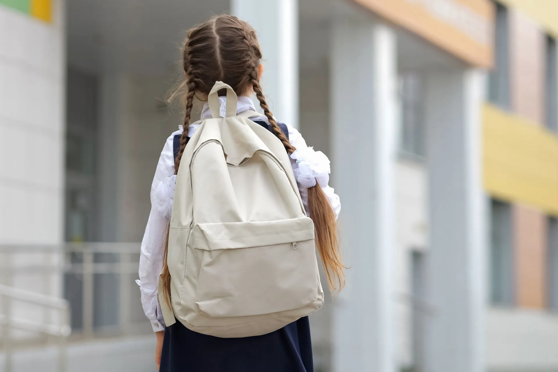 Crianças uniformizadas em uma sala de aula de uma escola particular, levantando as mãos.