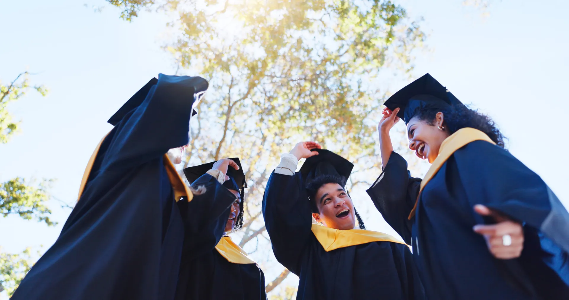 Estudantes universitários de beca jogando os chapéus para o alto em comemoração.