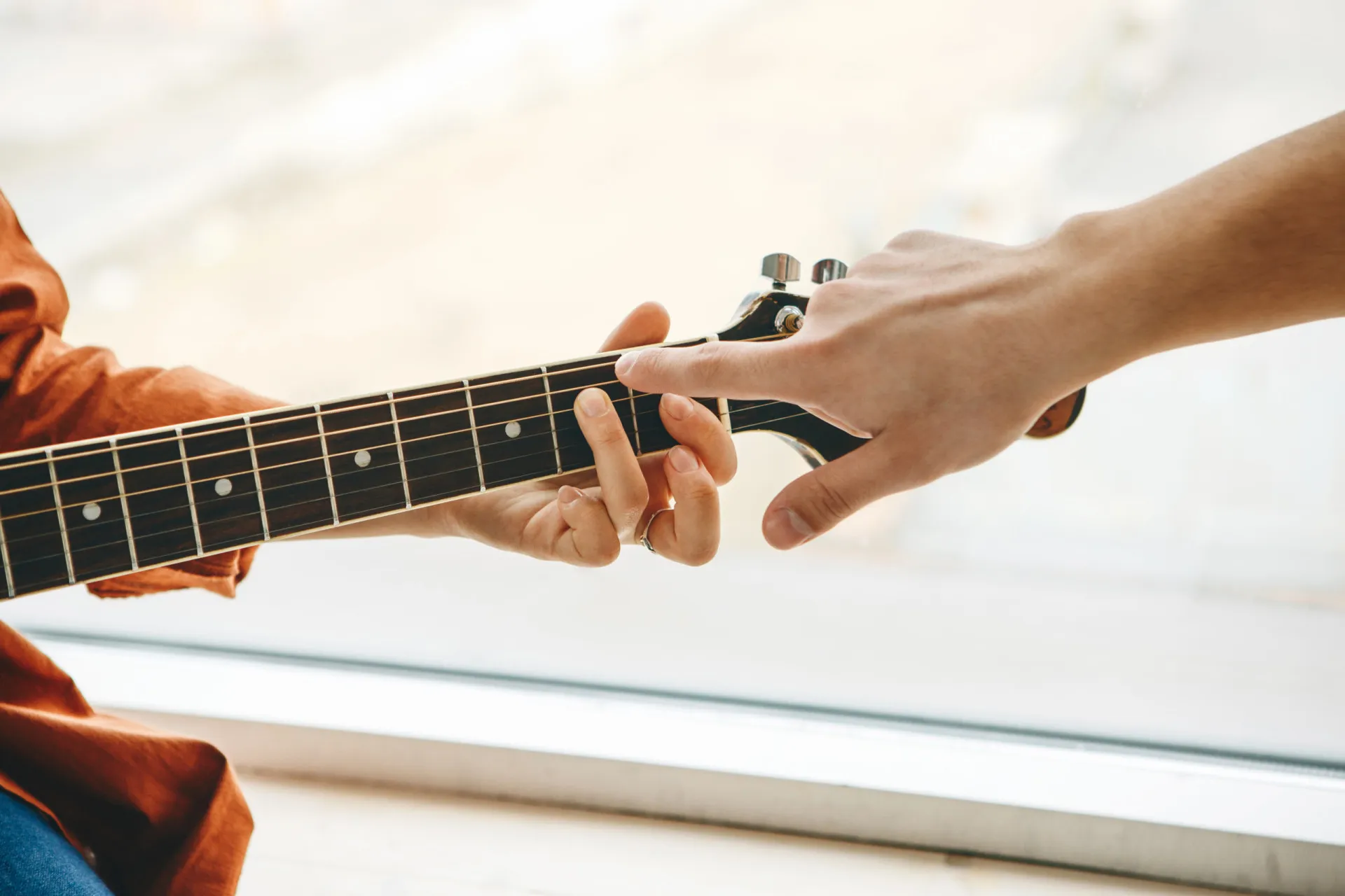Menina tocando violino em uma aula de música com a professora ao lado.