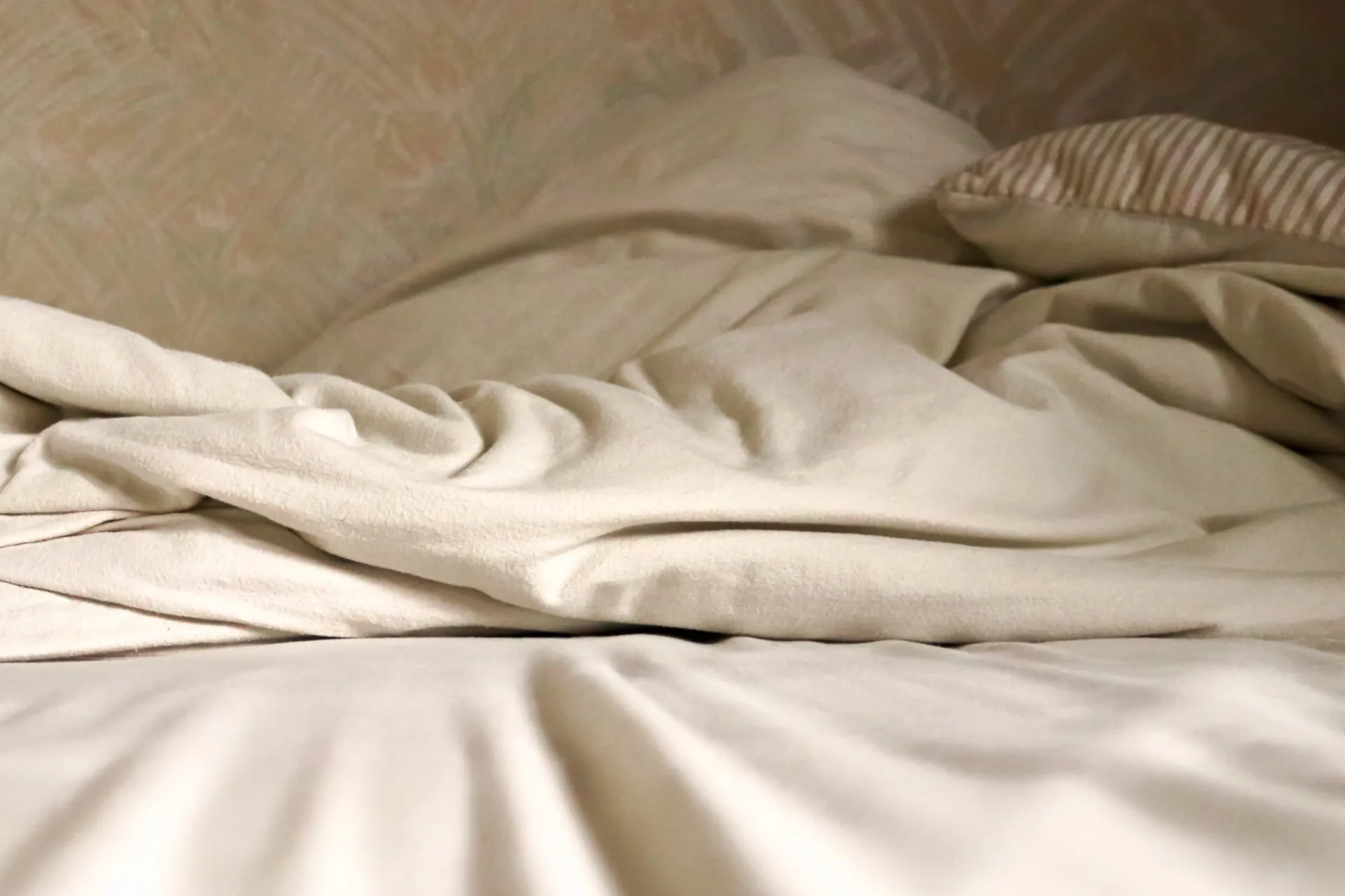 Uma pessoa aconchegada na cama com lençóis de flanela xadrez, transmitindo uma sensação de calor e conforto.