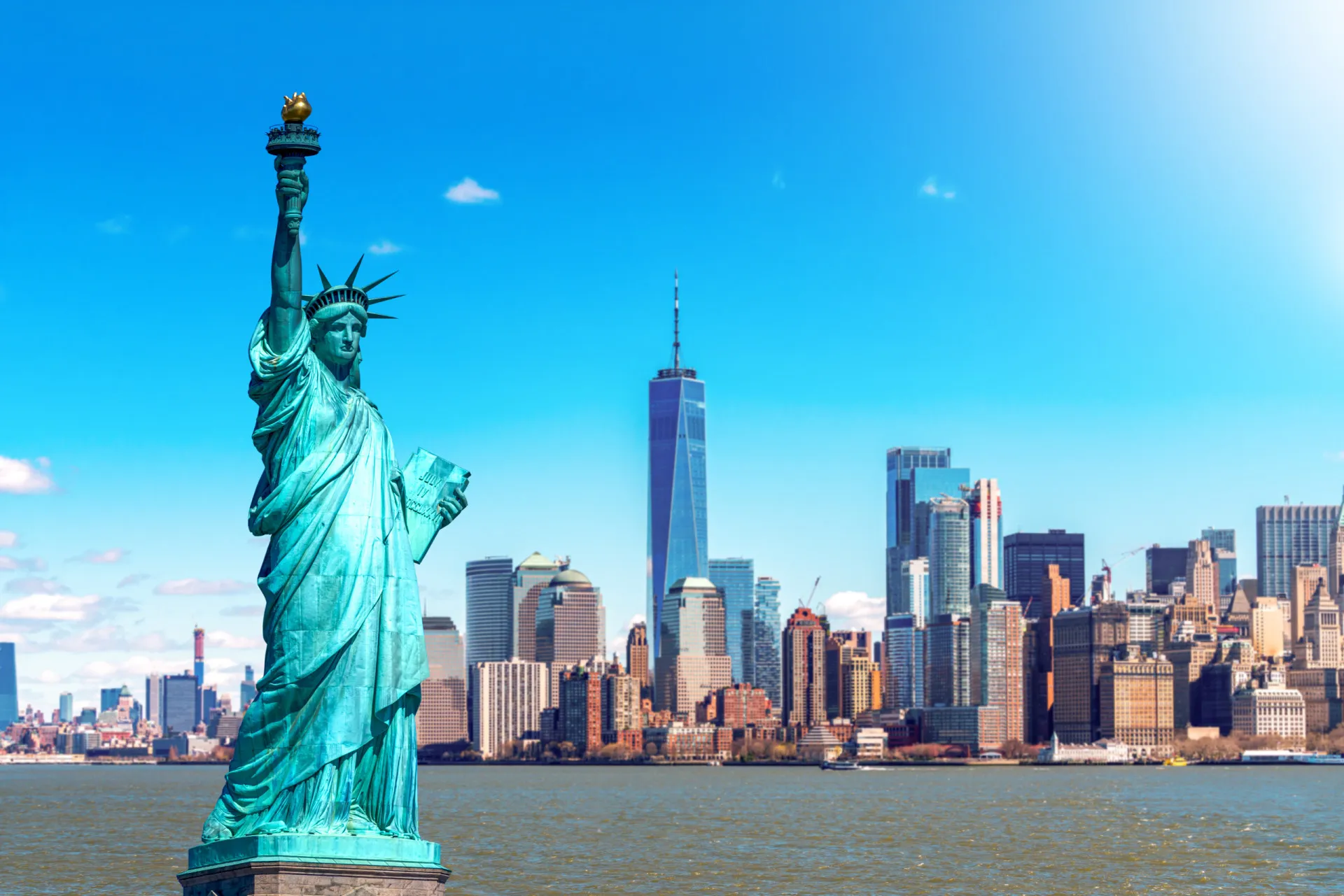 Estátua da Liberdade em Nova York, com a bandeira dos EUA ao fundo.