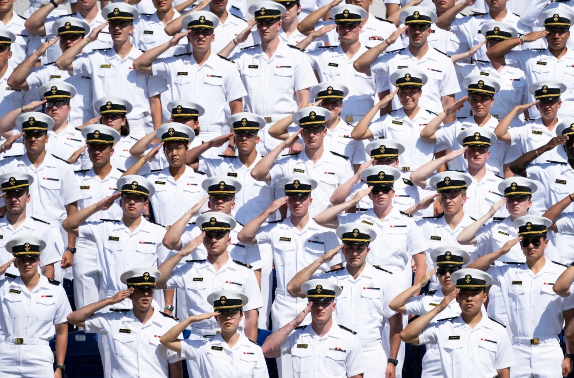 Cadetes da Academia Naval dos Estados Unidos jogando seus quepes para o alto na formatura.