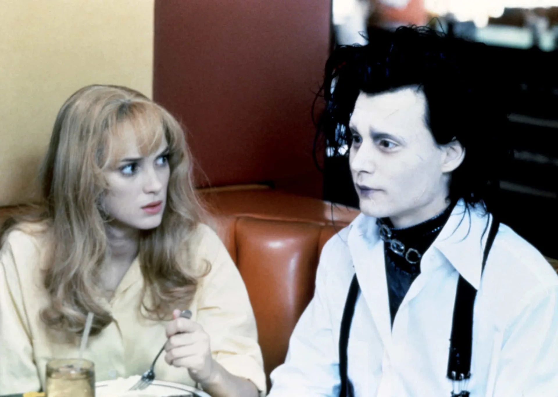 Johnny Depp como Edward Mãos de Tesoura e Winona Ryder como Kim, em uma cena delicada e gótica.