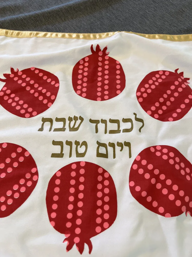 Detalhe de uma veste sacerdotal bordada com imagens de romãs douradas.