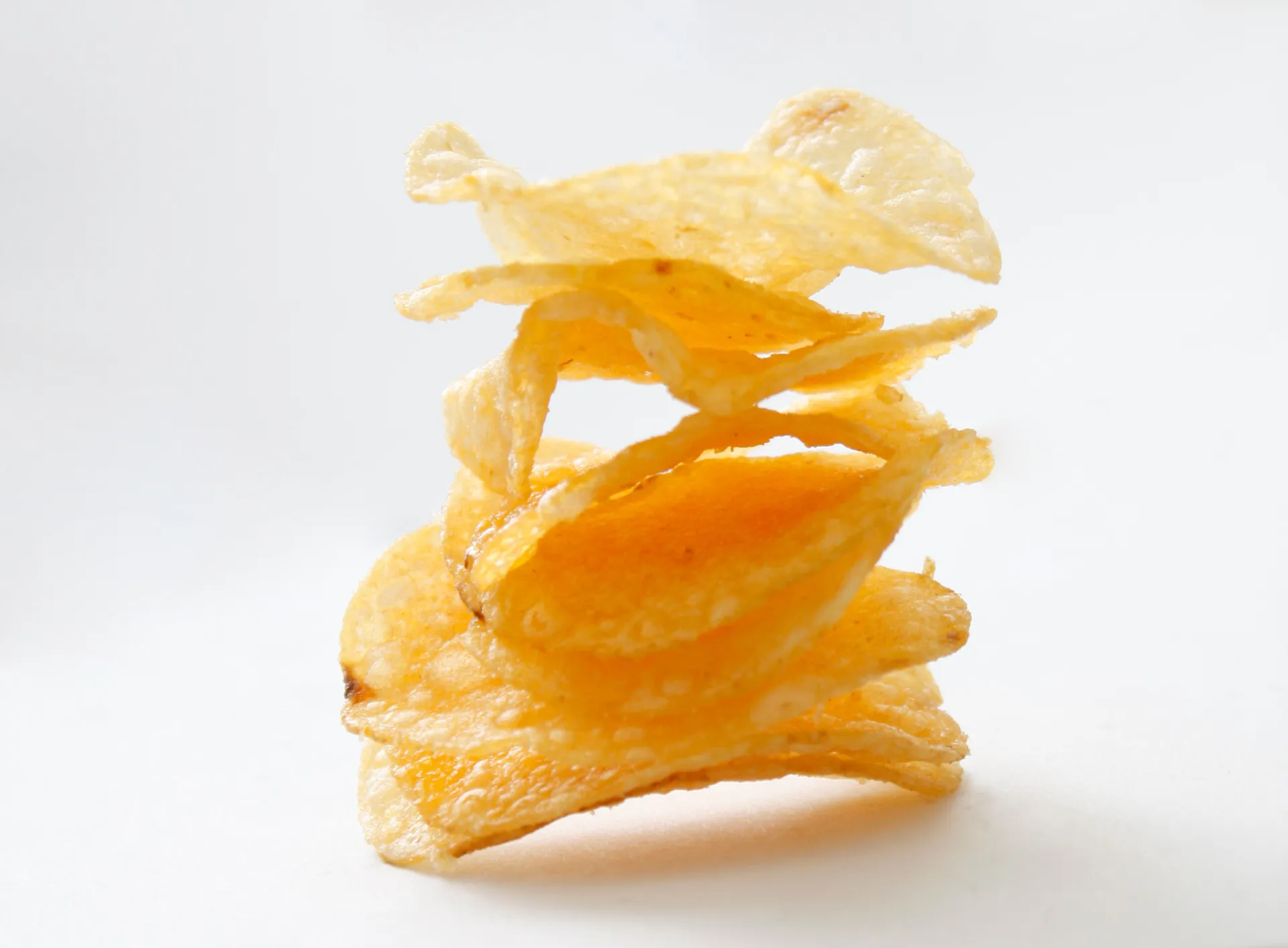 Pacotes de salgadinhos e batatas fritas empilhados, representando alimentos processados.