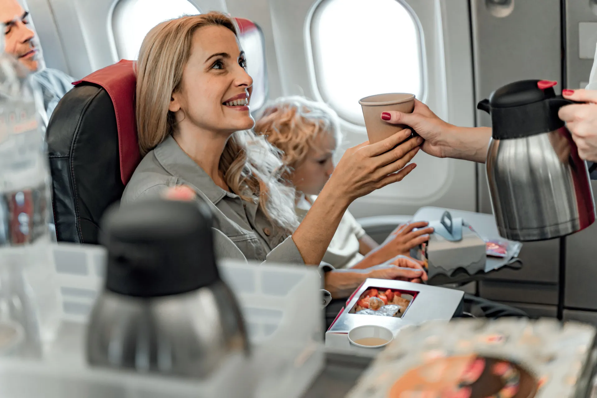 Uma pessoa com expressão de desconforto, segurando a cabeça, sentada em um assento de avião.
