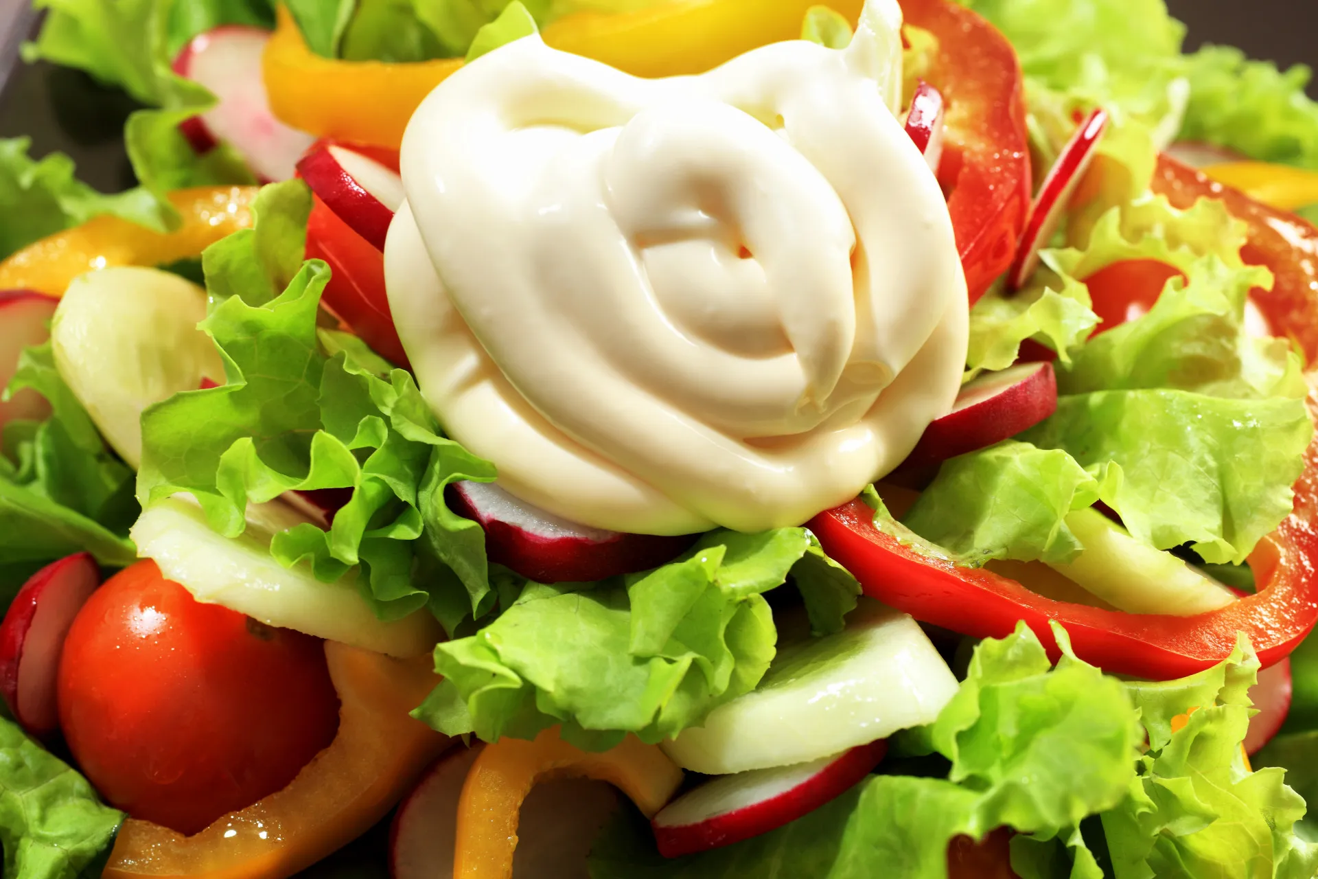Salada sendo regada com um molho industrializado cremoso.