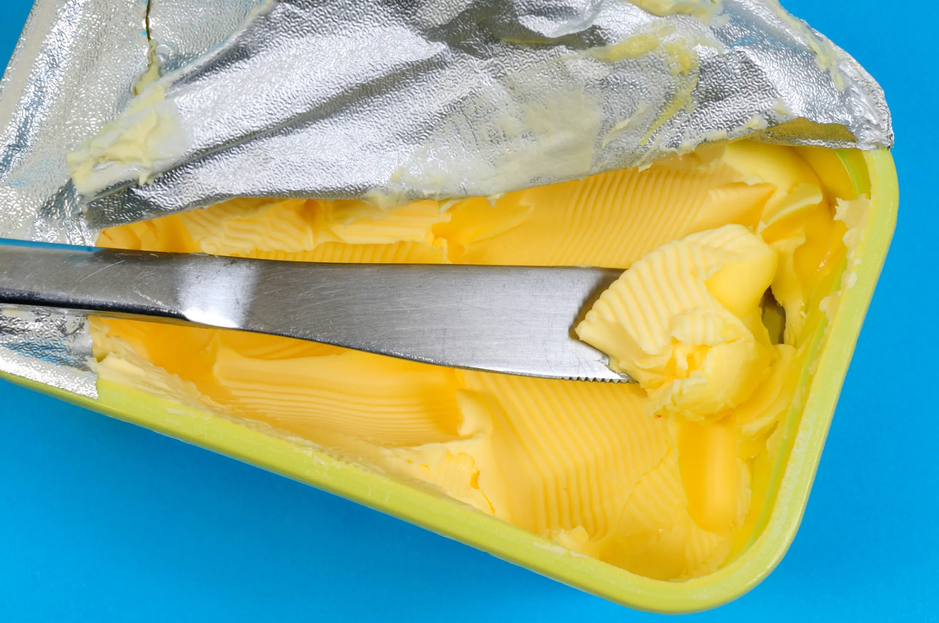 Pote de margarina ao lado de um pão, parecendo uma alternativa à manteiga.