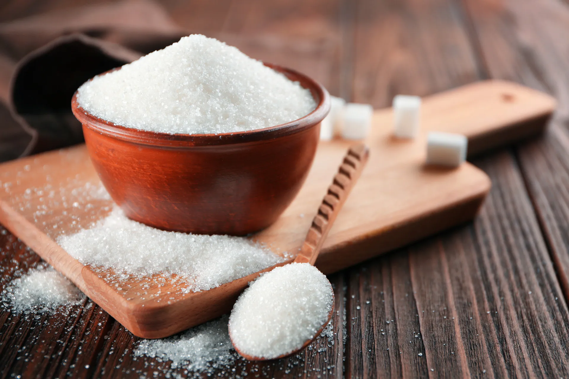 Cubos de açúcar branco refinado e açúcar mascavo orgânico lado a lado.