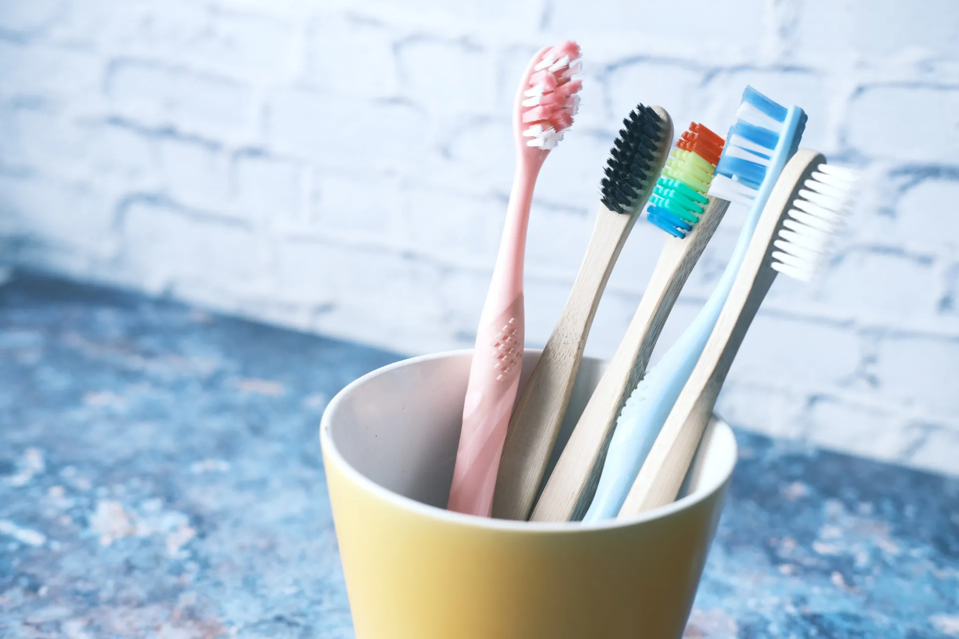 Um porta-escovas de dente branco com várias escovas coloridas, um item comum em banheiros.