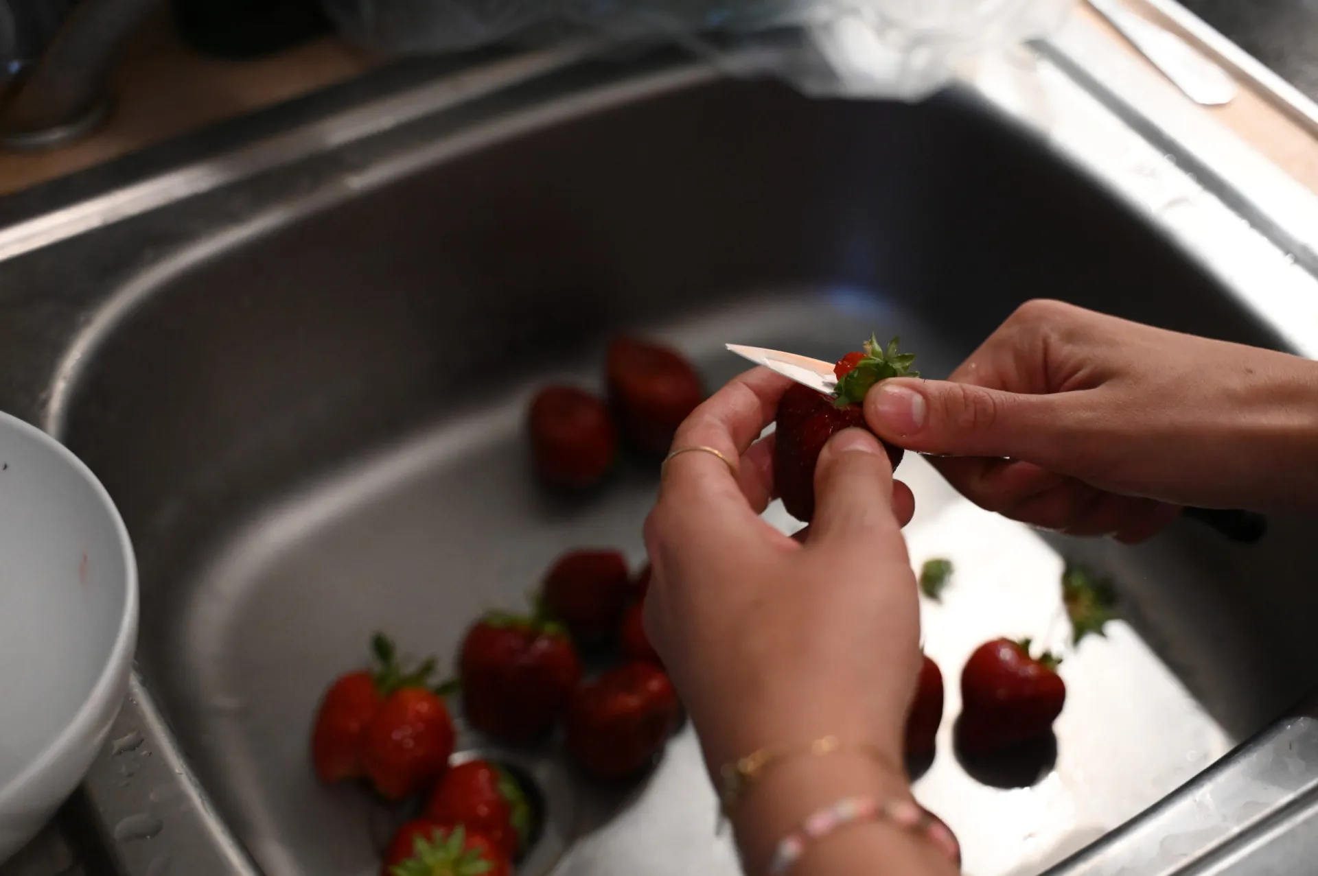 Uma pia de cozinha cheia de louça suja e restos de comida, um ambiente úmido e propenso a bactérias.