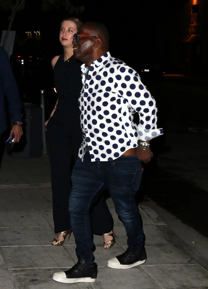Randy Jackson puxando para cima sua calça larga que não parava de cair durante um evento.
