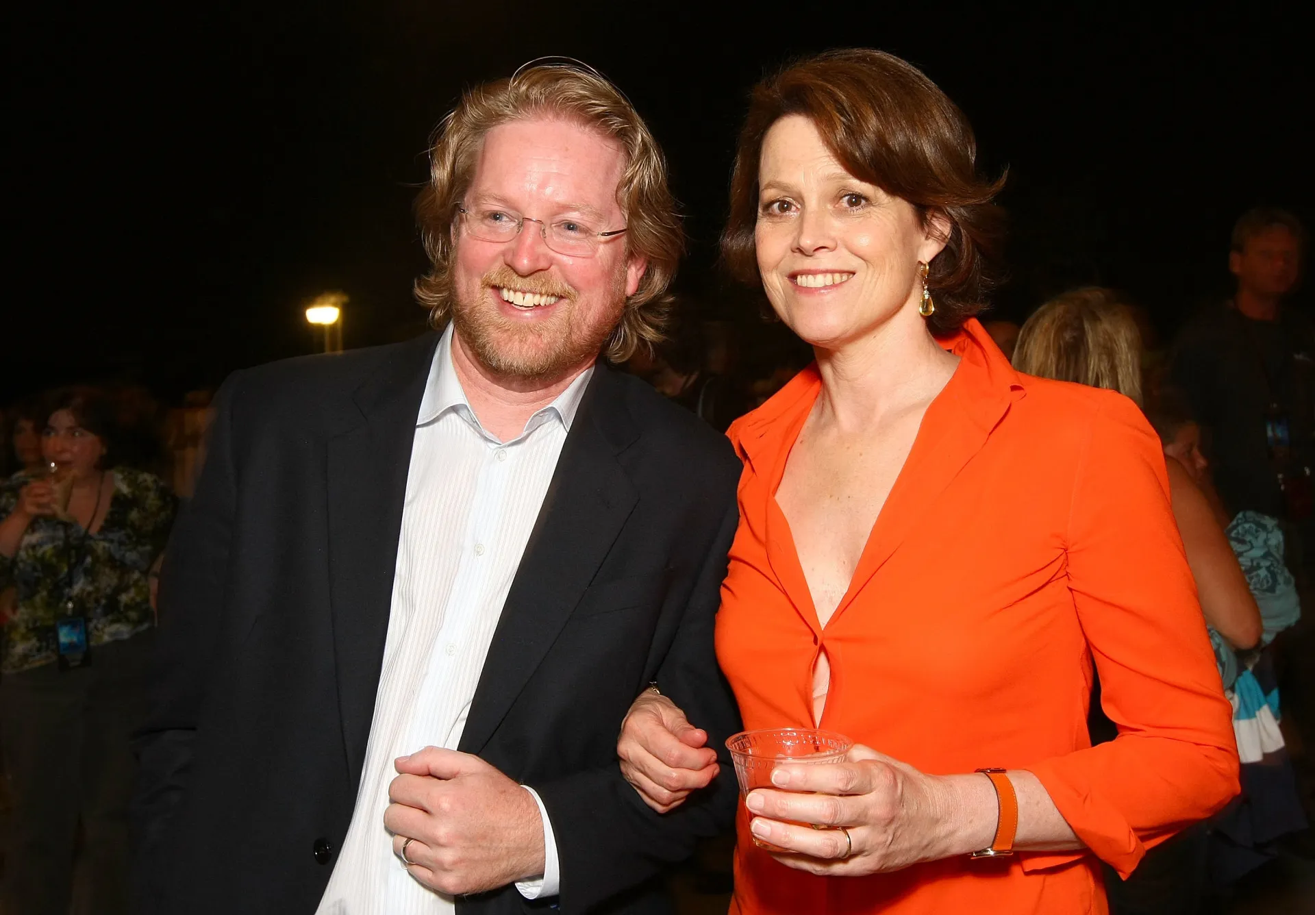 Sigourney Weaver com uma blusa de botões que se abriu, revelando sua roupa íntima.