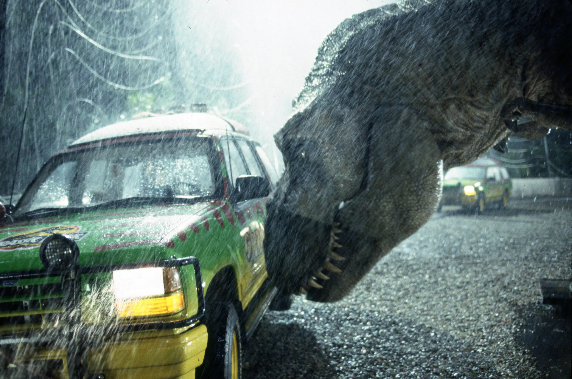 Cena do filme 'Jurassic Park' com o Tiranossauro Rex se aproximando dos personagens.