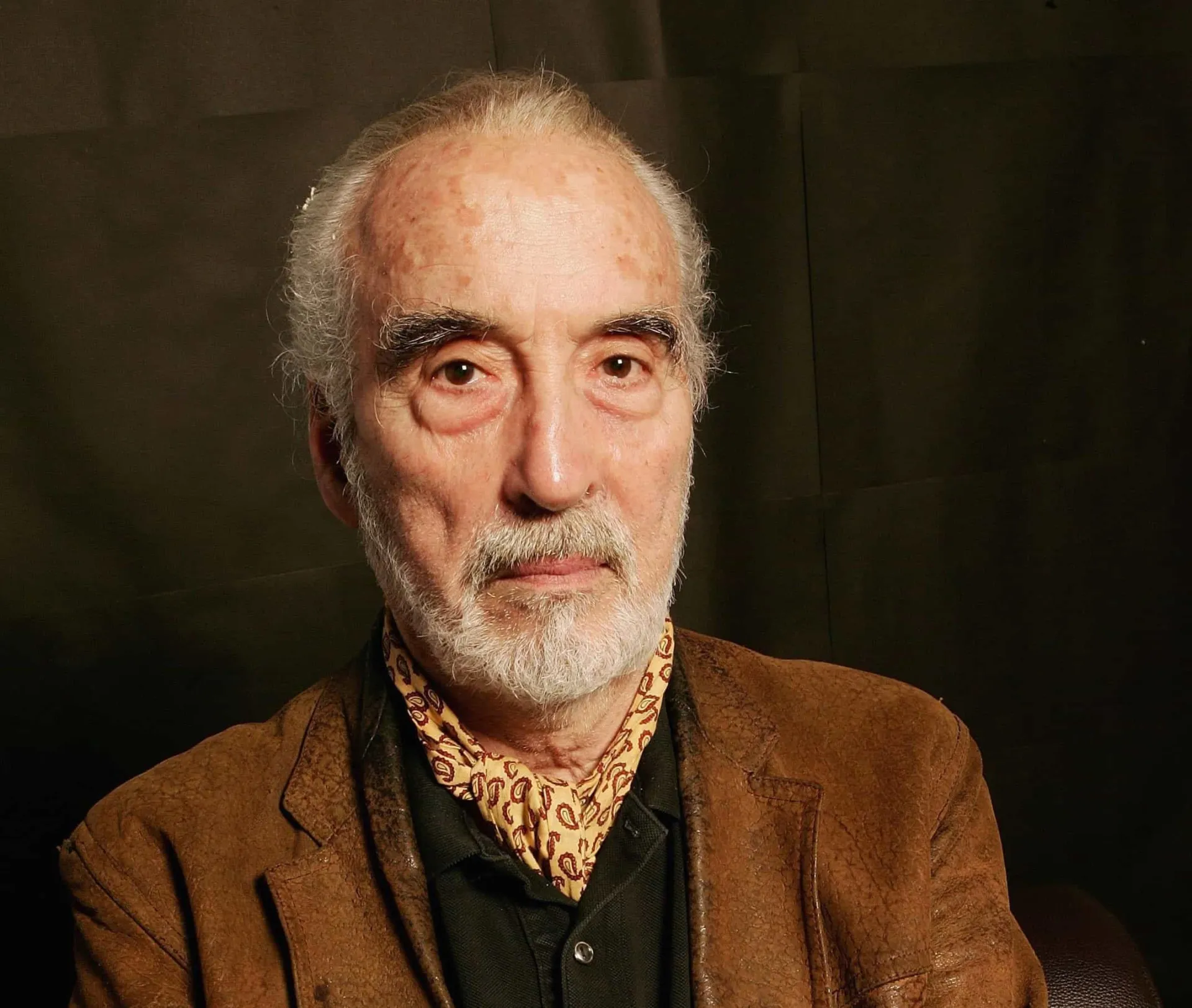 Christopher Lee caracterizado como o Conde Drácula, com um olhar intenso e presas à mostra.