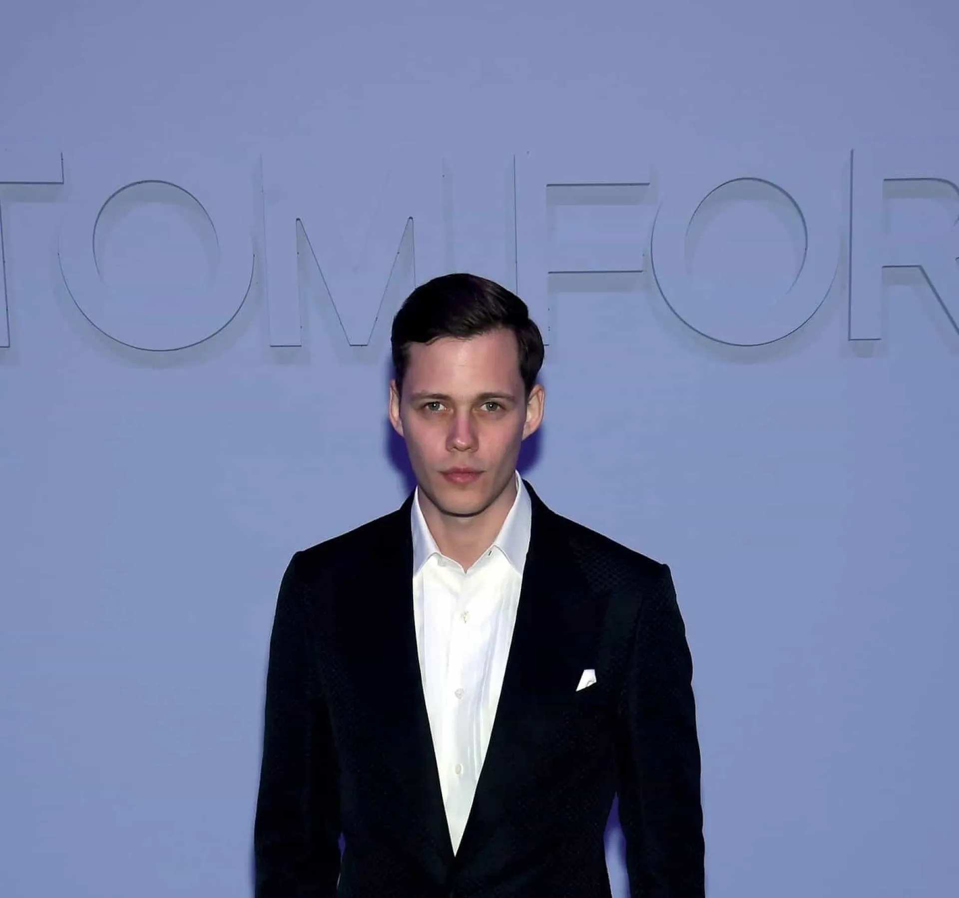 Bill Skarsgård na pele do palhaço Pennywise no remake de 'It', com um sorriso maligno e assustador.