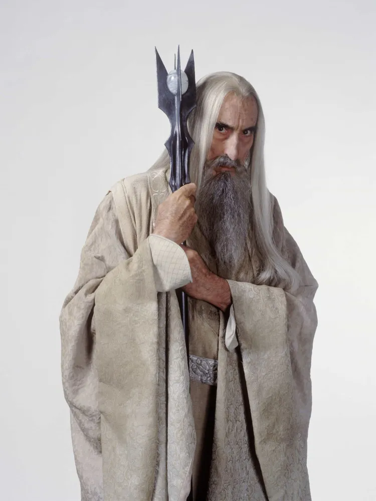 Christopher Lee como o mago Saruman na trilogia 'O Senhor dos Anéis', com longos cabelos brancos e um cajado.