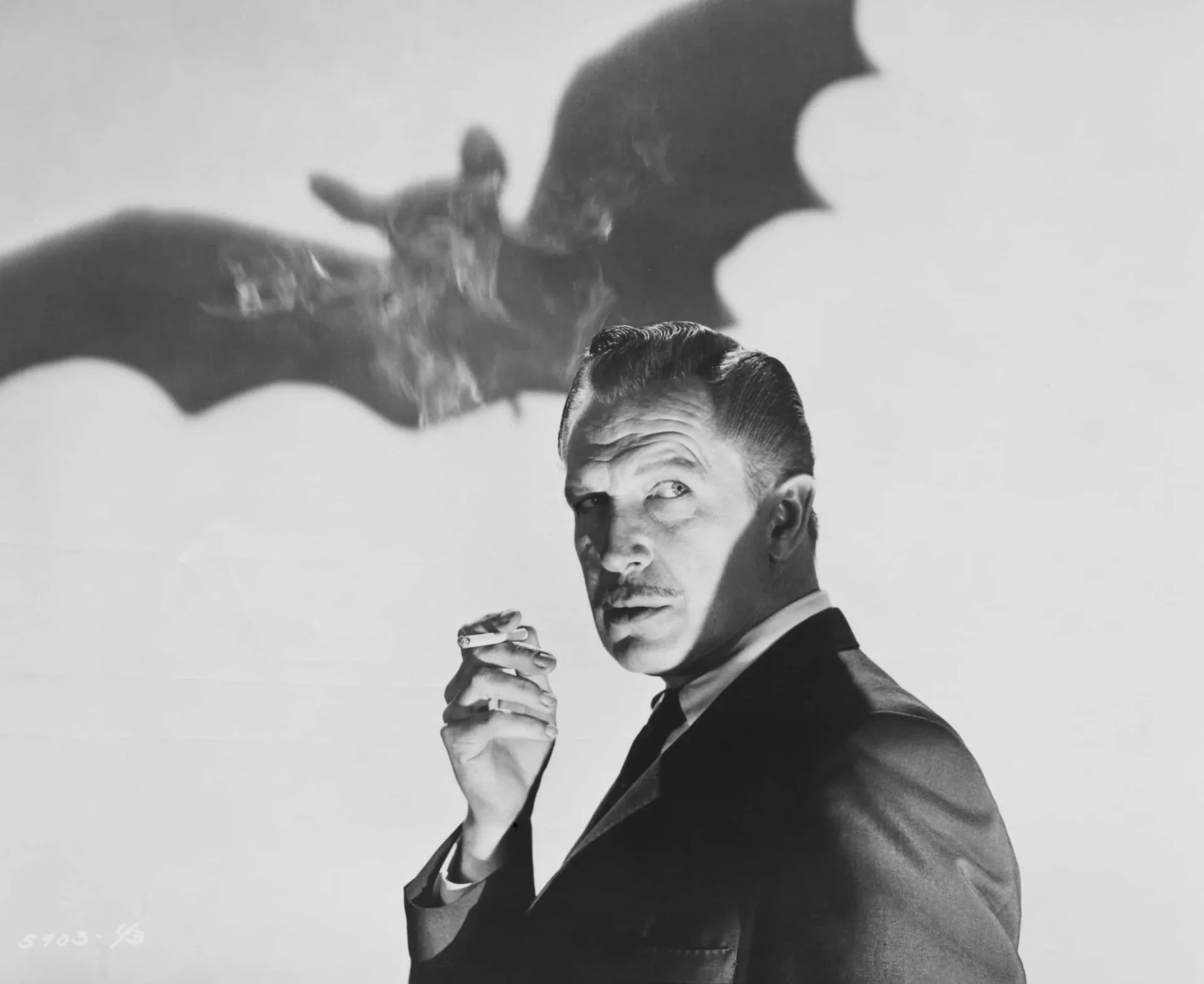 Vincent Price com um sorriso enigmático, segurando uma caveira em uma de suas mãos.