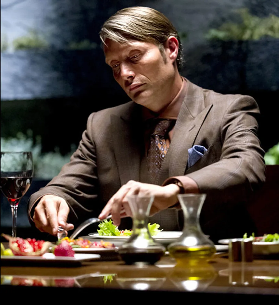 Mads Mikkelsen com um olhar frio e calculista, característico de seus papéis como vilão.