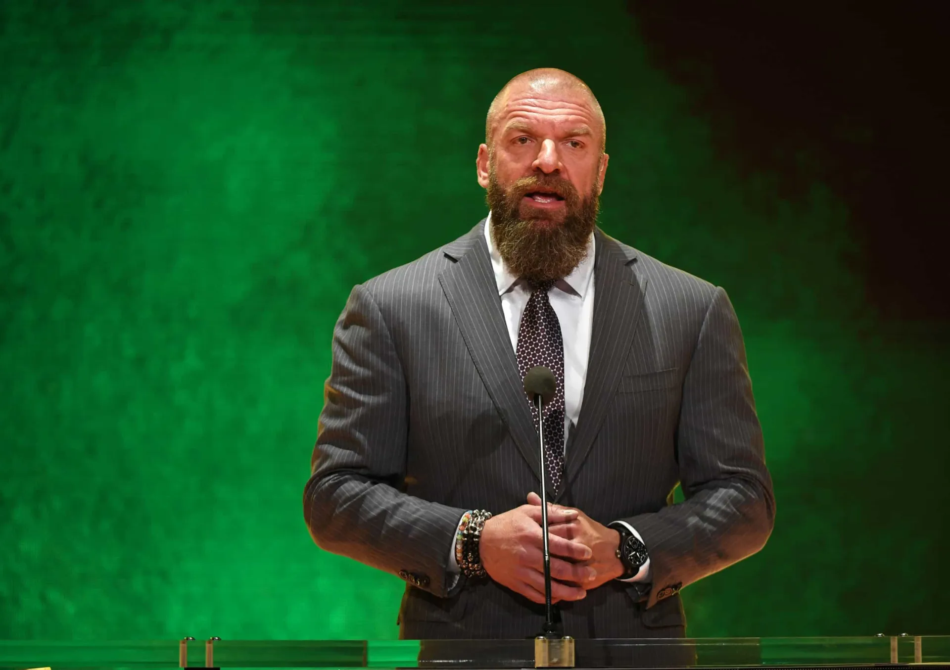 O lutador e executivo da WWE, Triple H, em um evento, com um físico imponente.