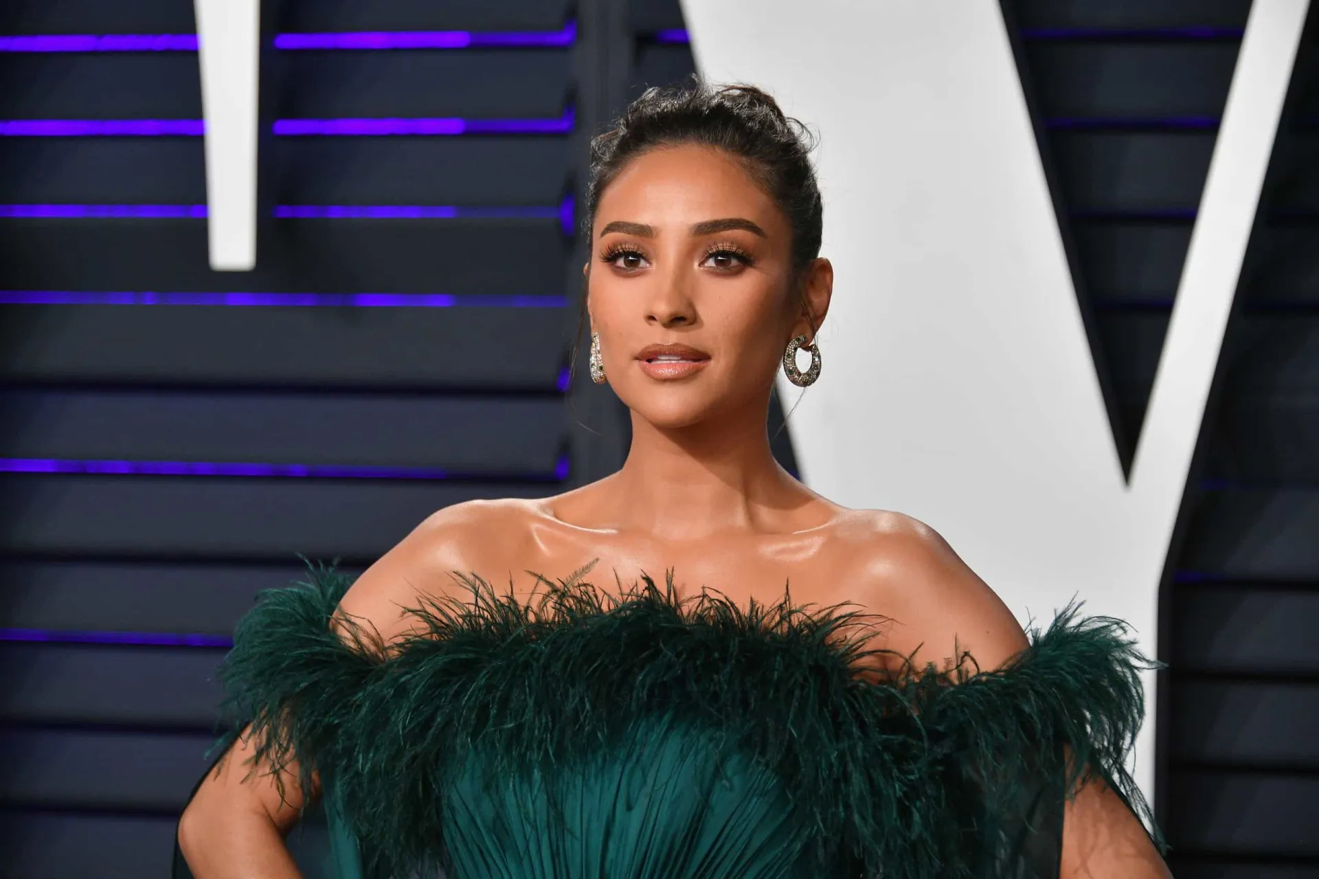 A atriz Shay Mitchell com um sorriso confiante, conhecida por seu estilo de vida aventureiro.