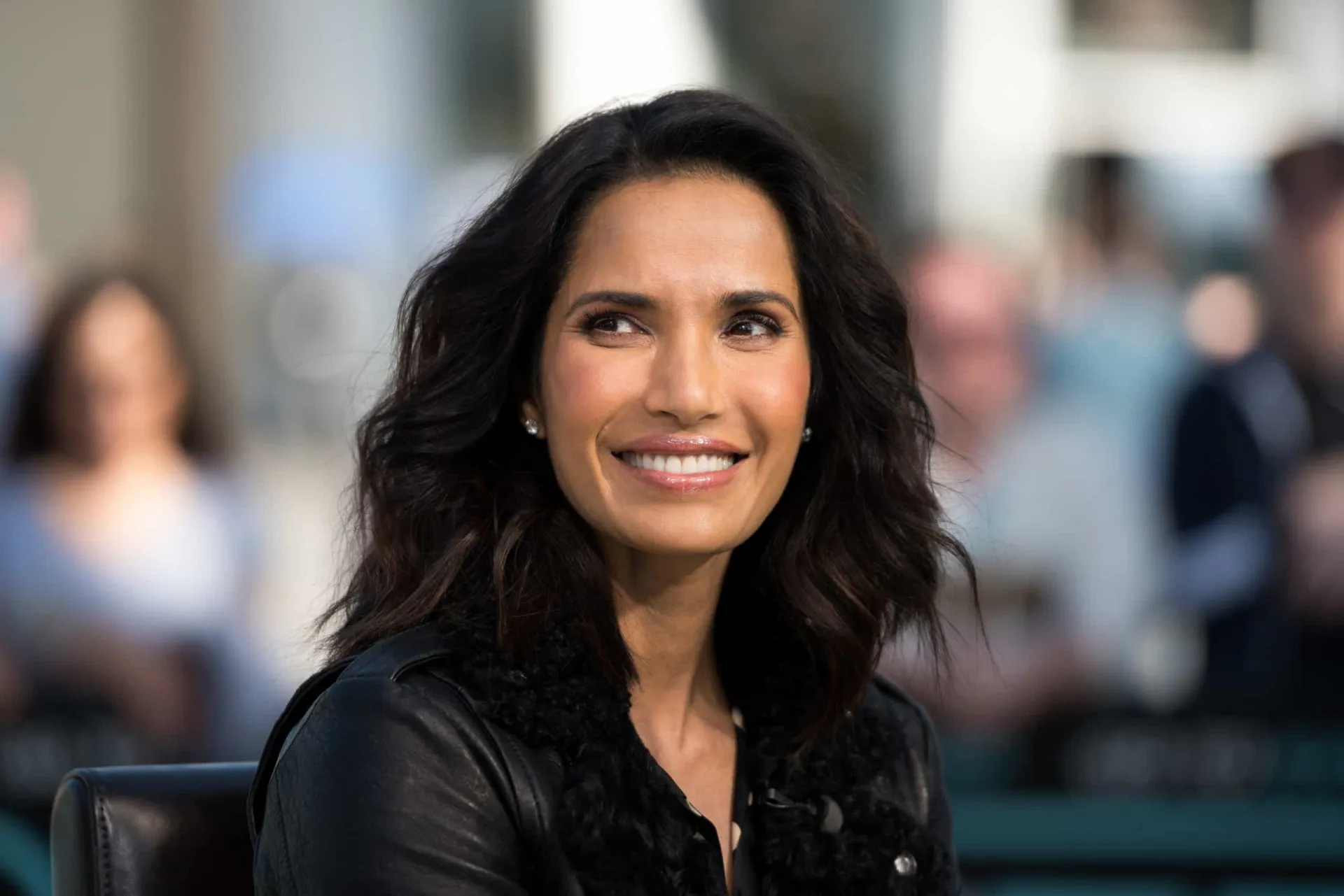 A apresentadora e autora Padma Lakshmi em um evento gastronômico, elegante e sorridente.
