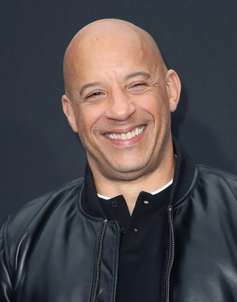 O ator Vin Diesel com seu visual característico, exibindo seus braços fortes.